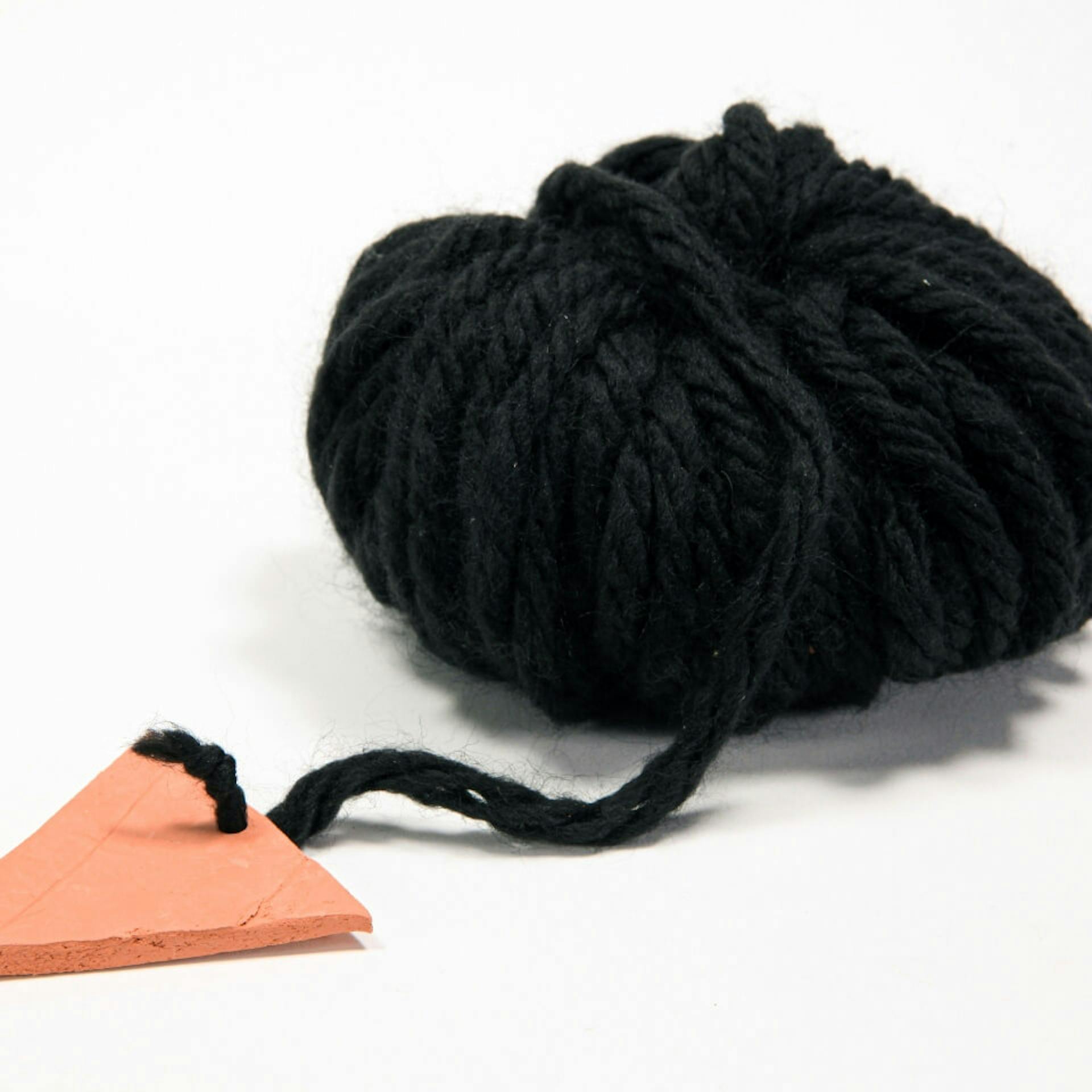 Schwarze Woll-Schnur ist an Tonform befestigt