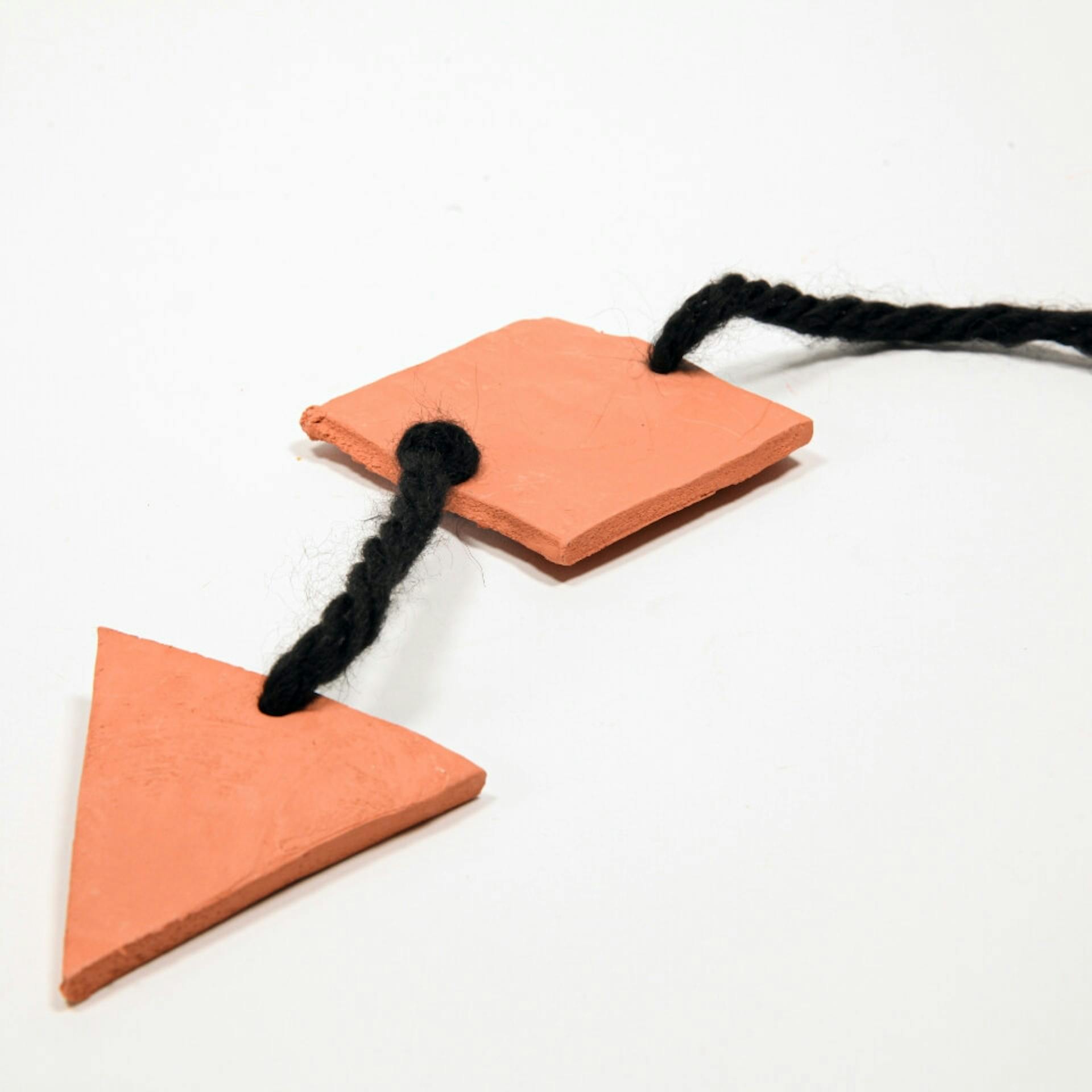 Zwei Tonformen sind an Woll-Schnur befestigt