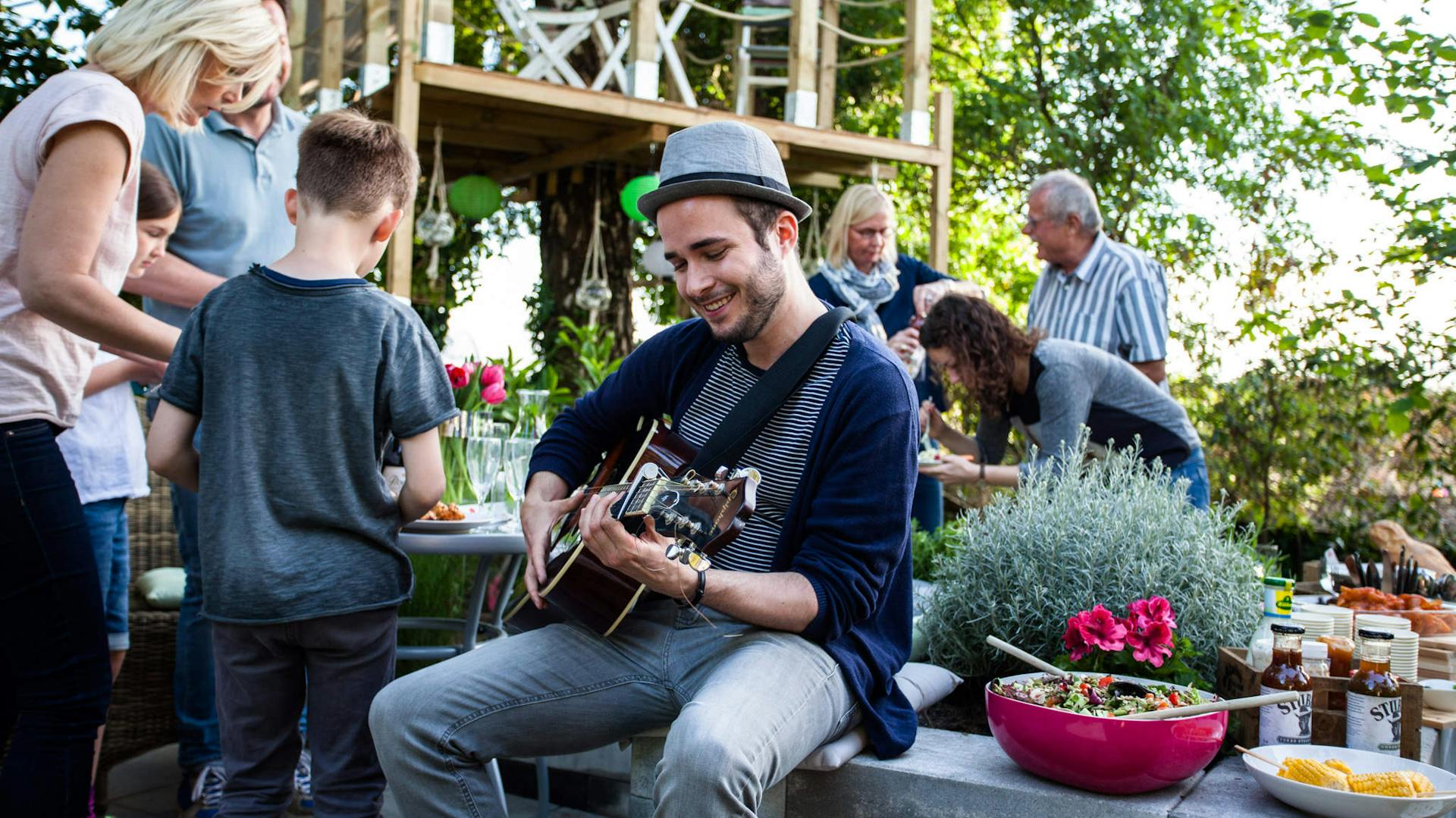 Junger Mann spielt Gitarre auf einer Grillparty