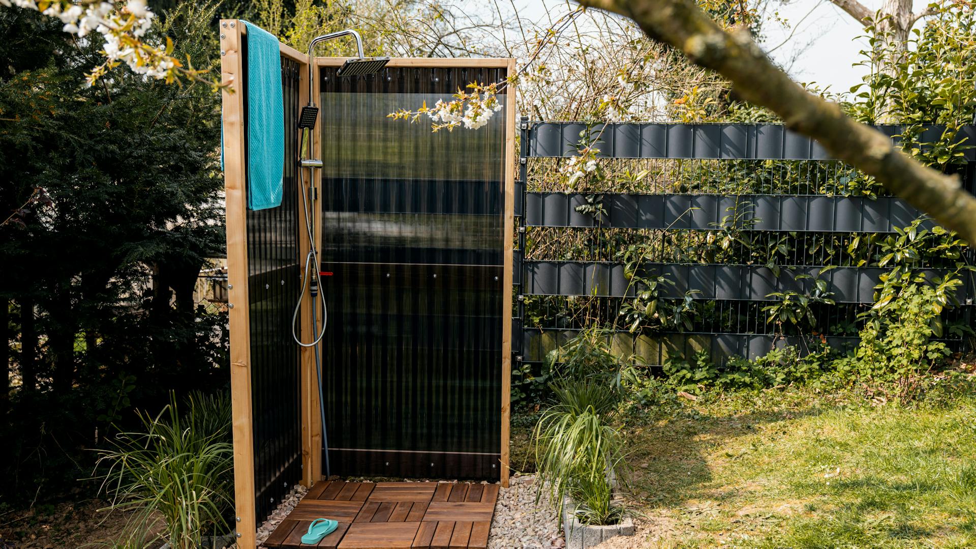 Eine selbst gebaute Gartendusche an einem sonnigen Tag im Garten
