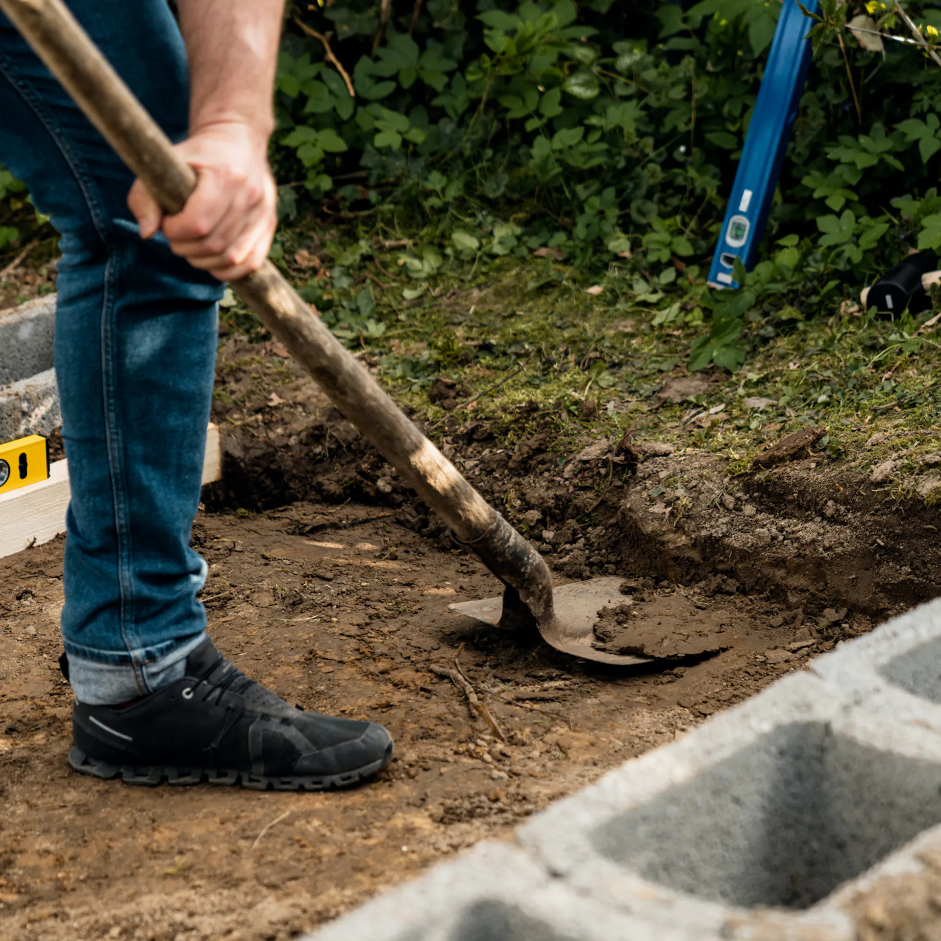 Muž odstraňuje pomocí lopaty zeminu do hloubky 20 cm