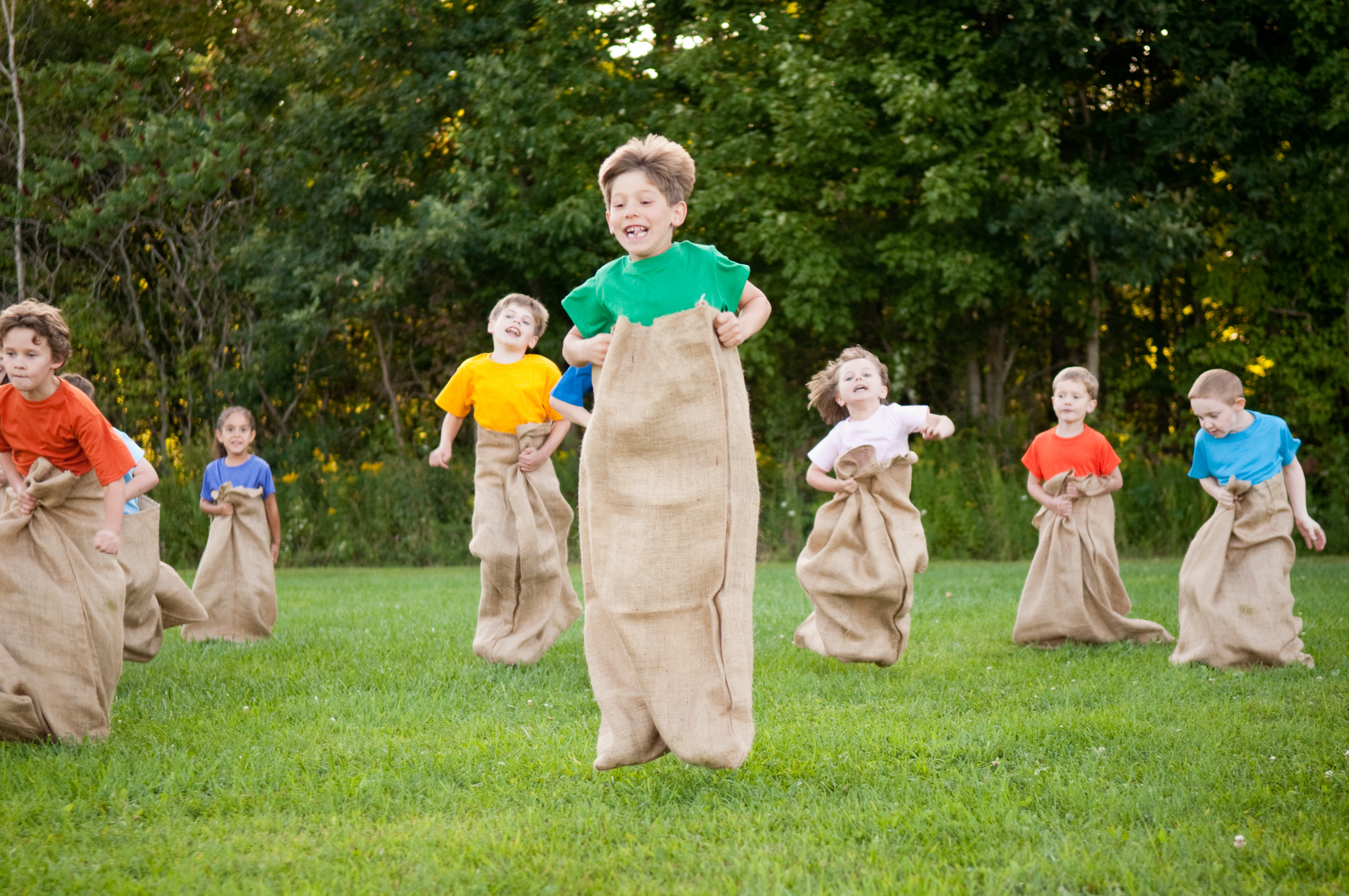 Kinder spielen im Garten Sackhüpfen.
