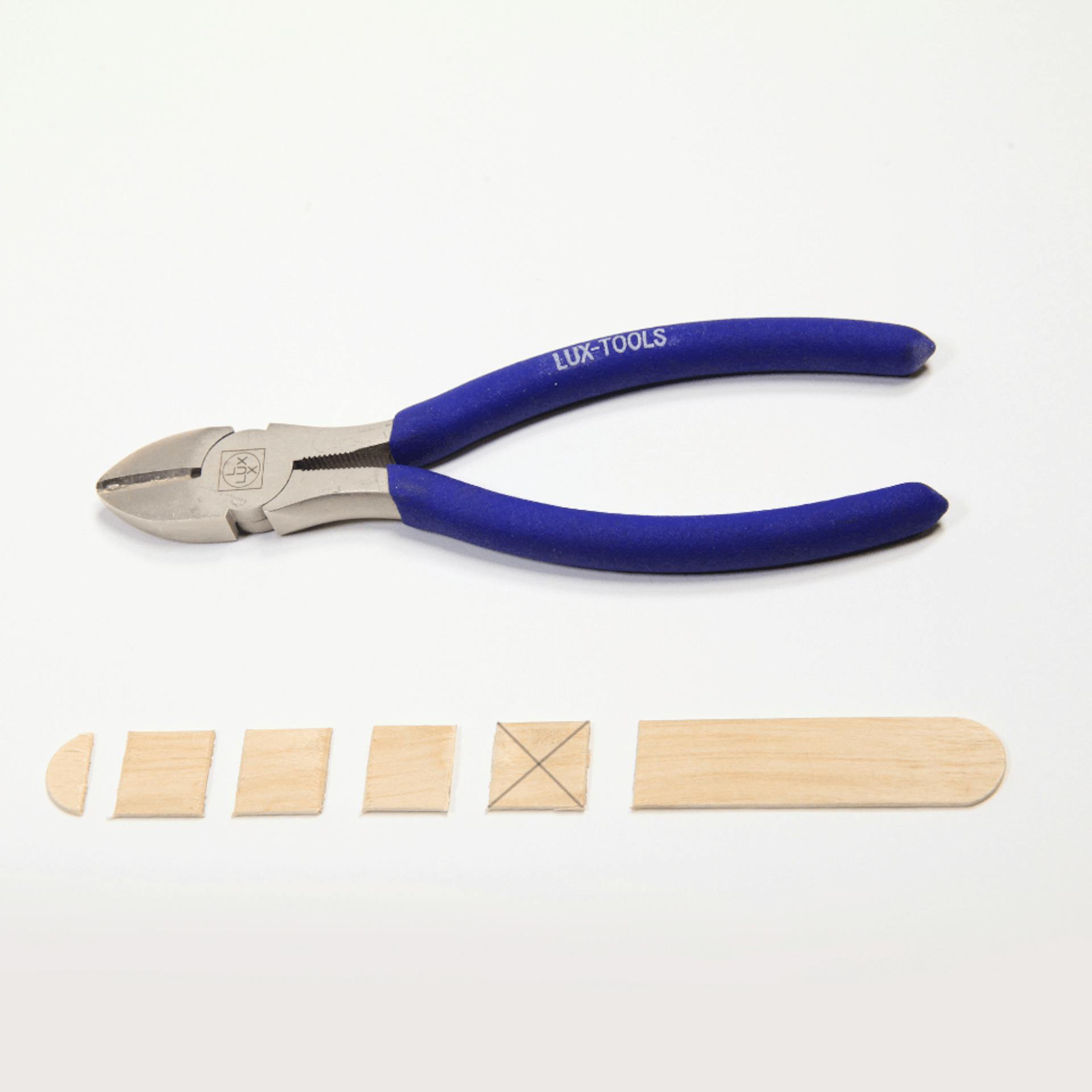 Eine Zange, darunter liegen einige zerteilte Holzstückchen.