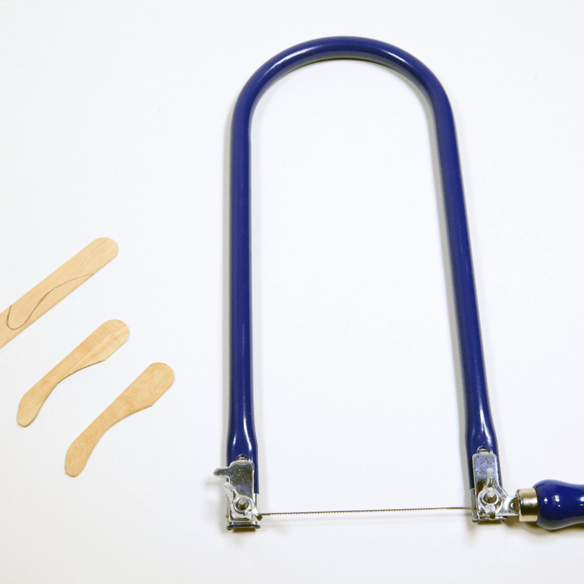 Zugesägte Holzstücke, daneben liegt eine Laubsäge.