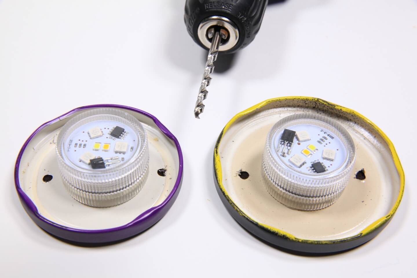 In ciascun coperchio vengono praticati due fori. Sullo sfondo si trova un trapano a batteria.