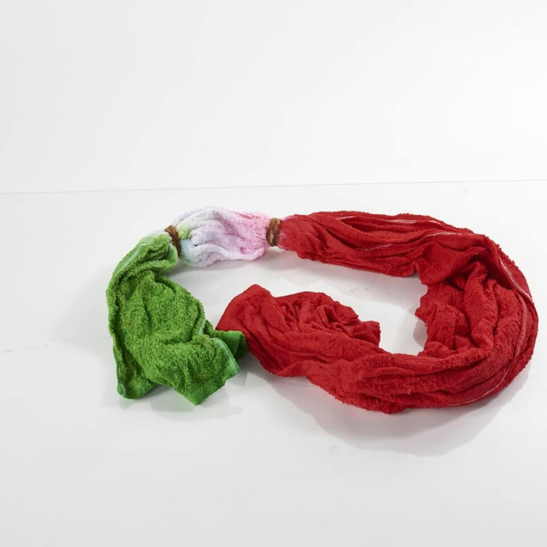 Es ist ein nasses Handtuch zu sehen. Es ist an einer Seite grün gefärbt, an der anderen Seite rot. In der Mitte ist es weiß.