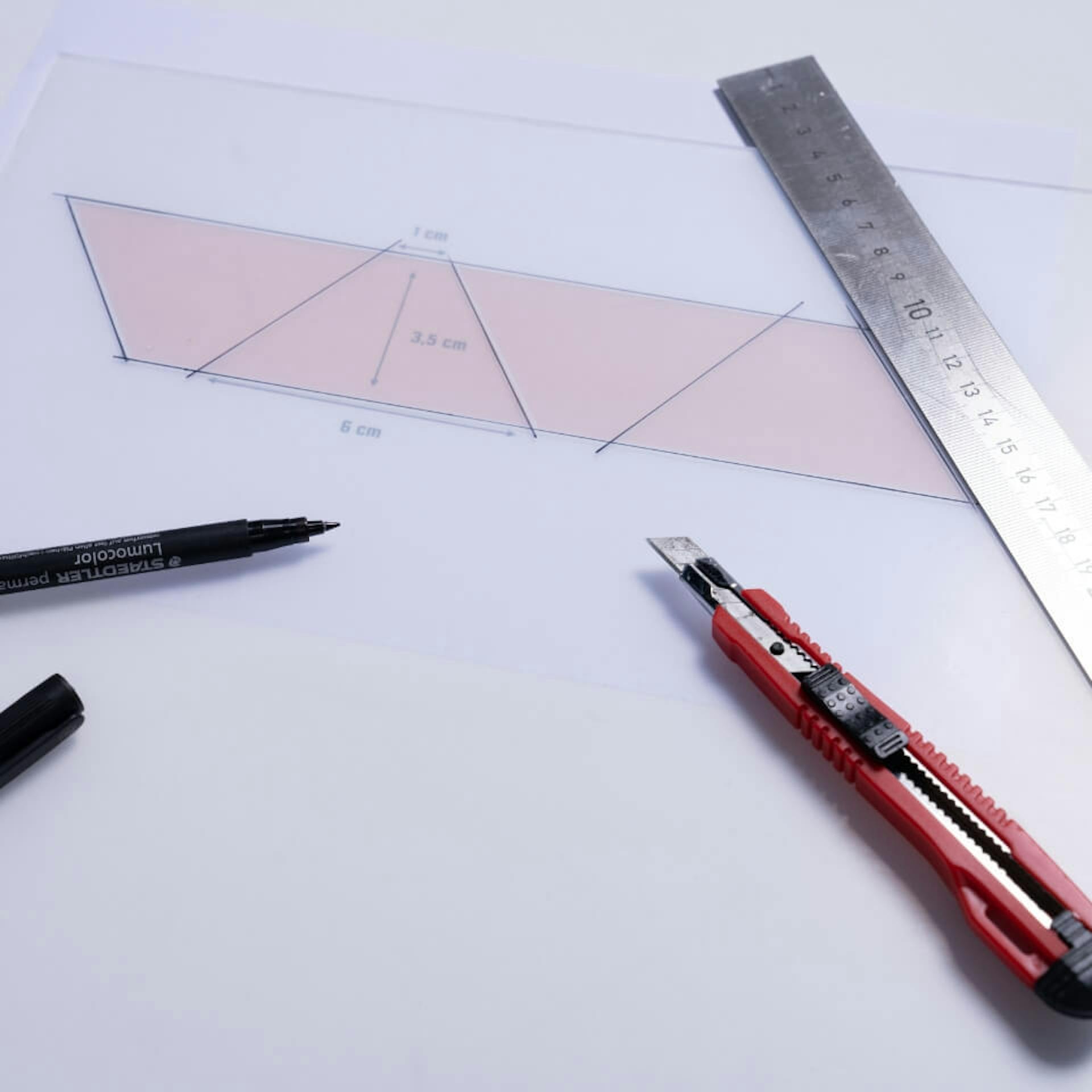 Cutter liegt neben Schablone, Folienstift und Lineal