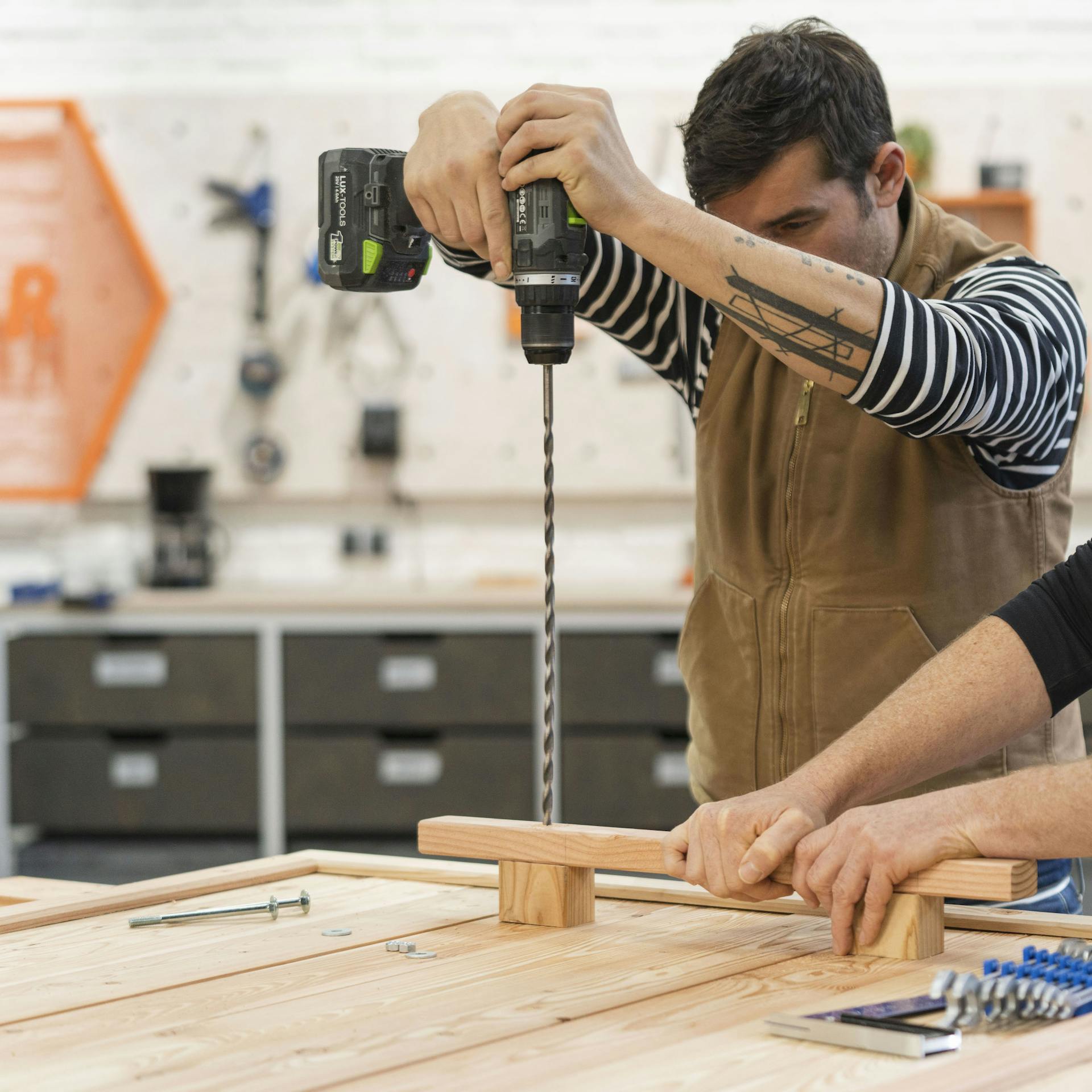 Mann bohrt mit Bohrer durch Holzgriff