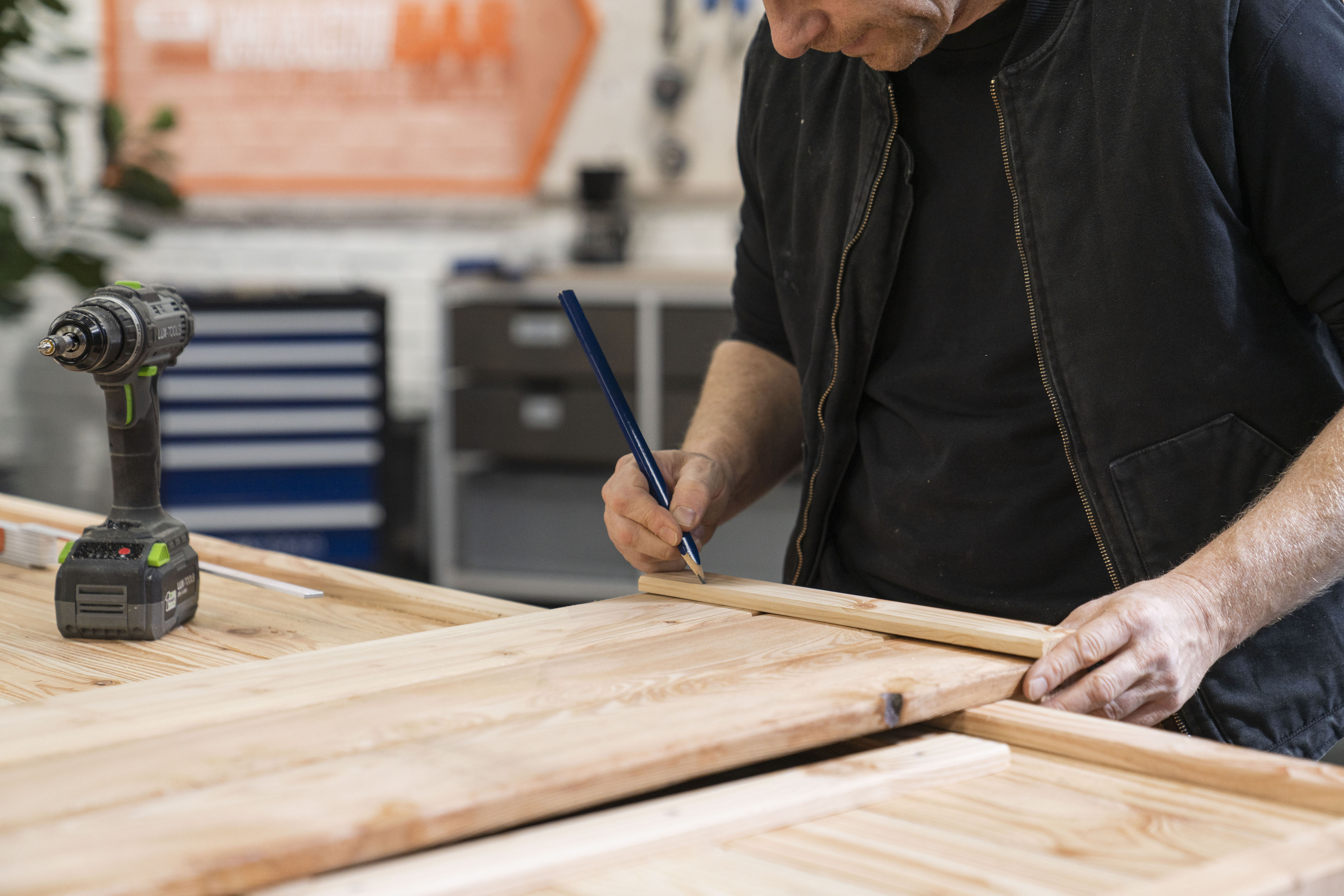 Mann zeichnet mit Bleistift auf Holz