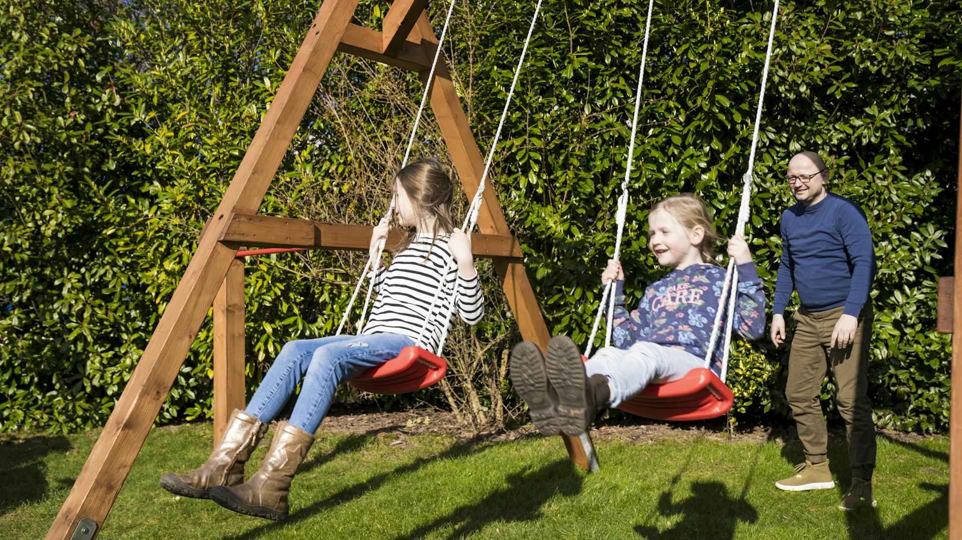 Schaukelnde Kinder im Garten