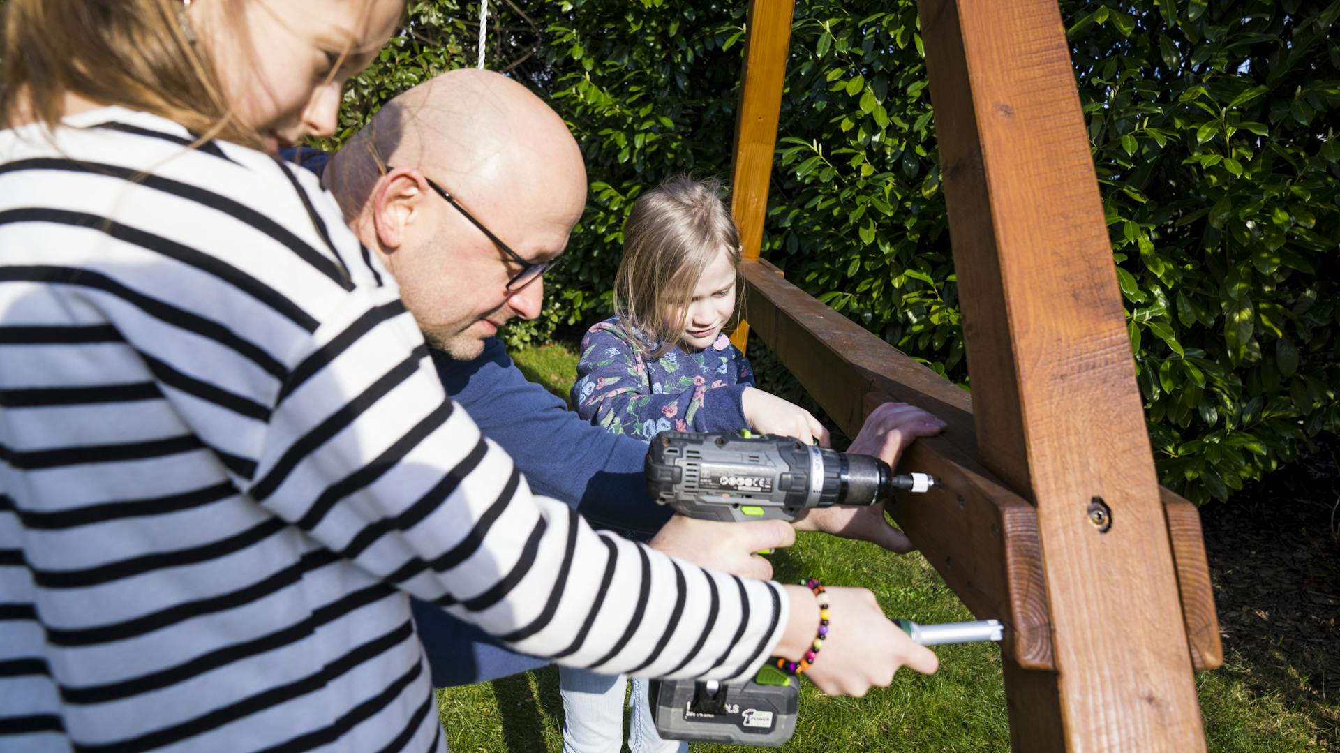 Töchter mit Vater bauen zusammen ein Schaukel