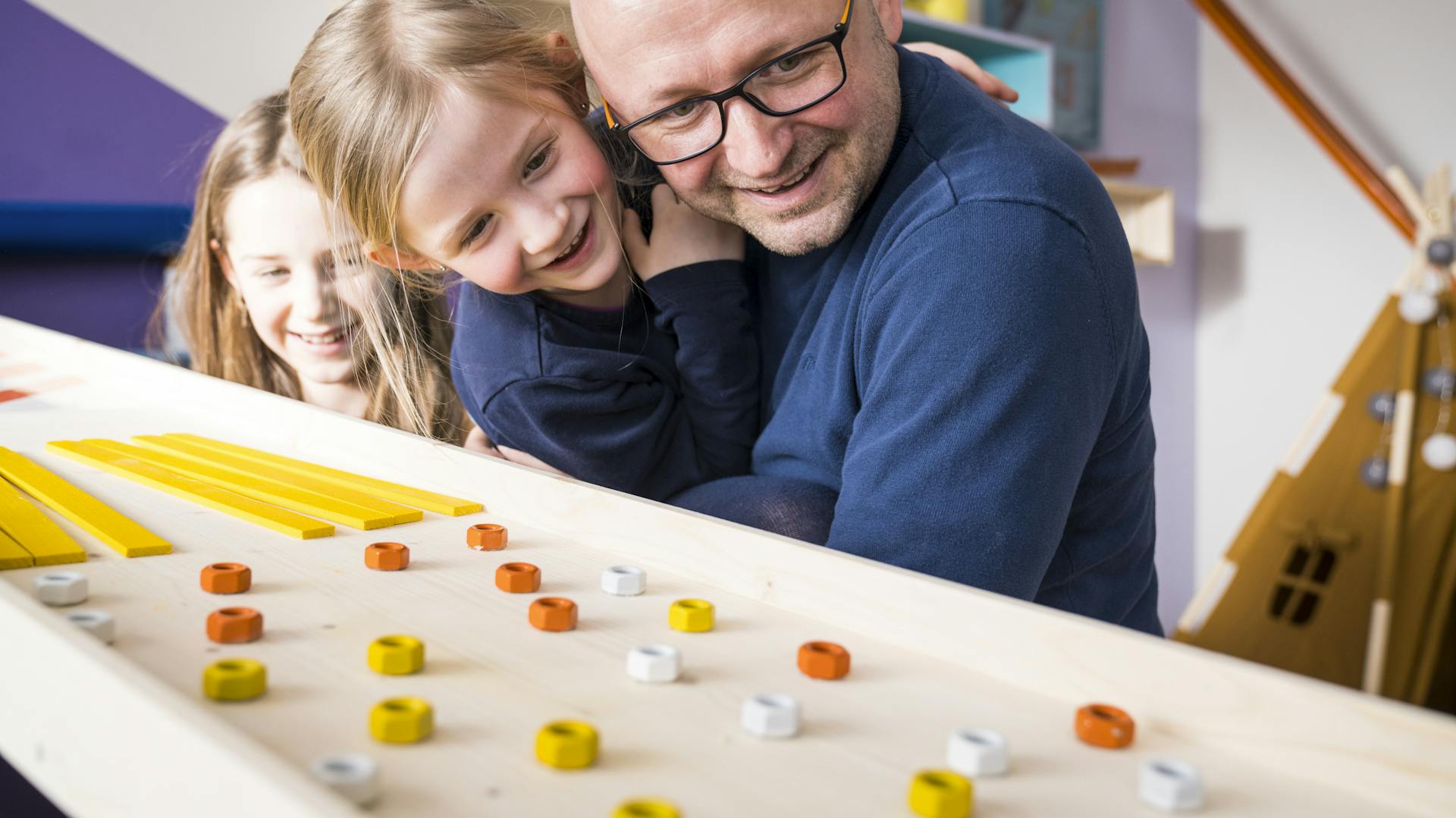 Vater und Töchter beobachten Murmelbahn