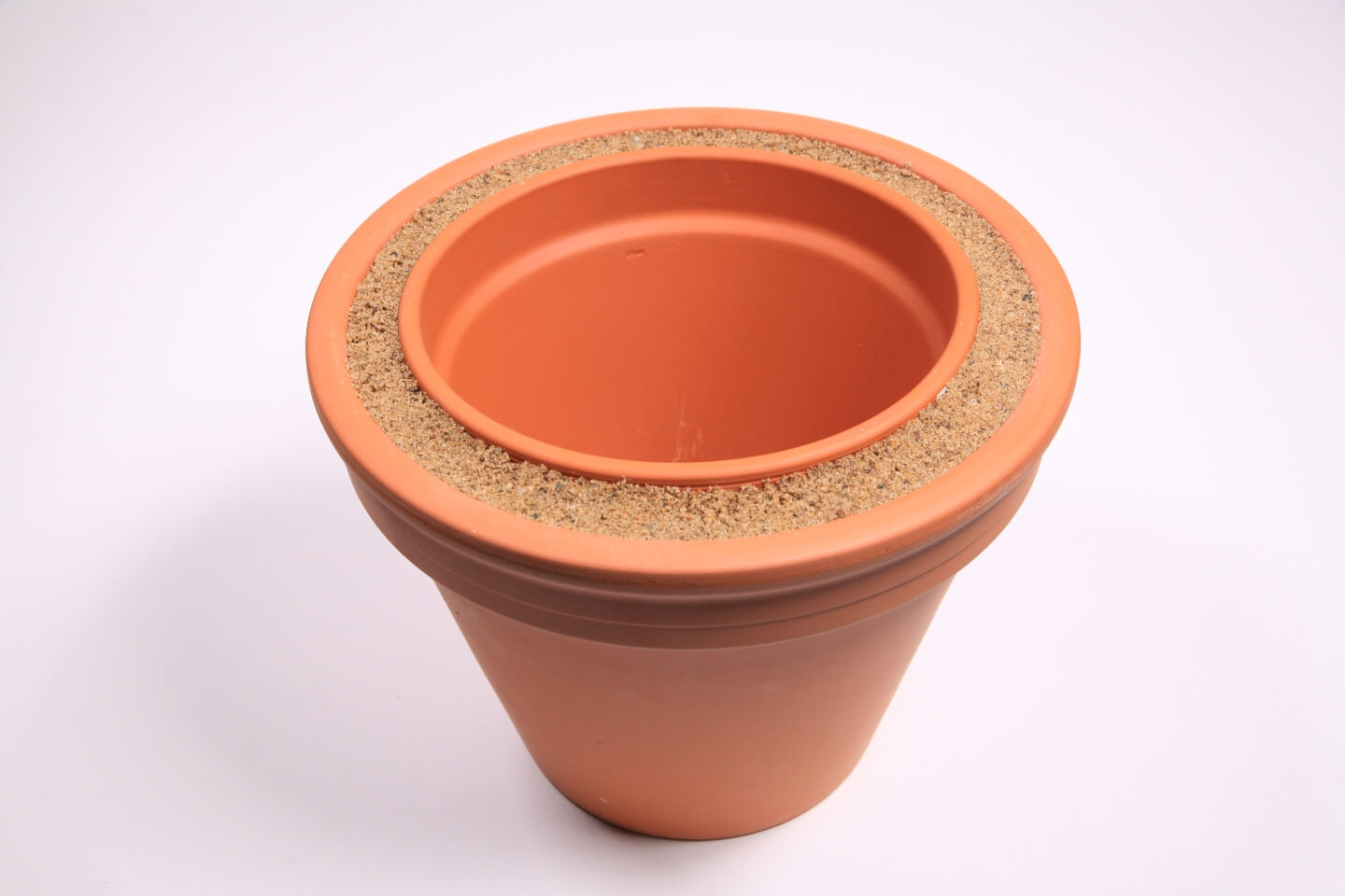 Im Zwischenraum zwischen den beiden Tontöpfen befindet sich Sand.
