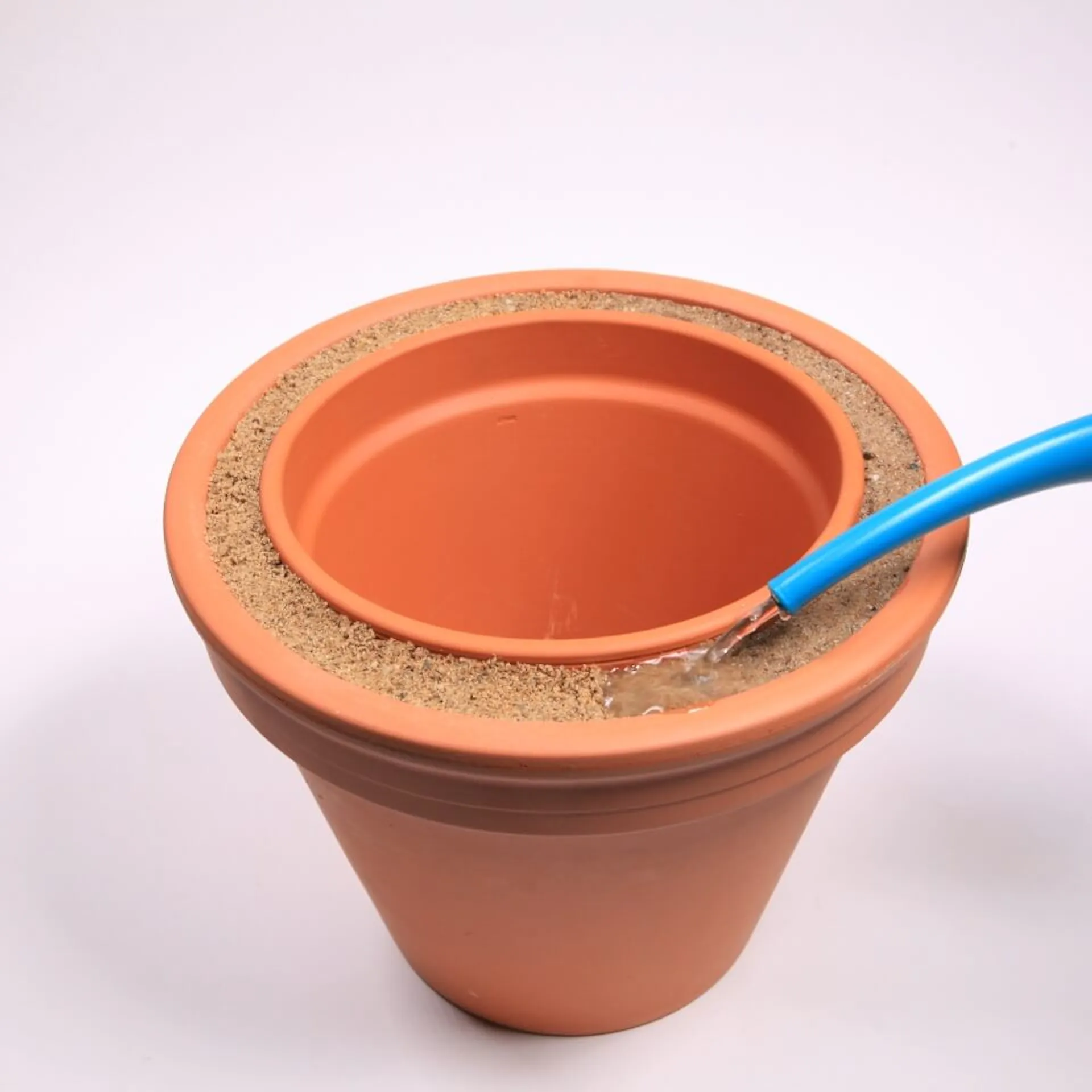 Eine Person tränkt den Sand im Zwischenraum per Gießkanne mit Wasser.
