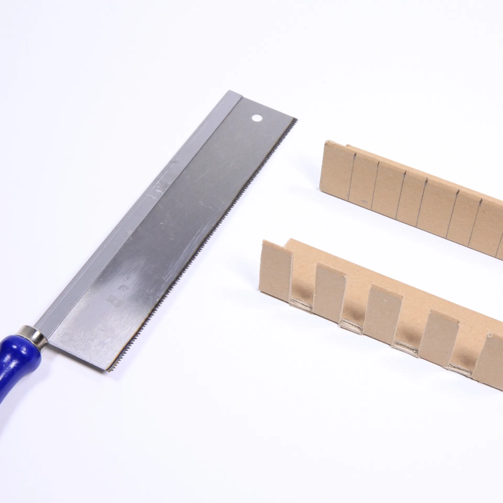 Handsäge liegt neben Kantenschutz aus Pappe