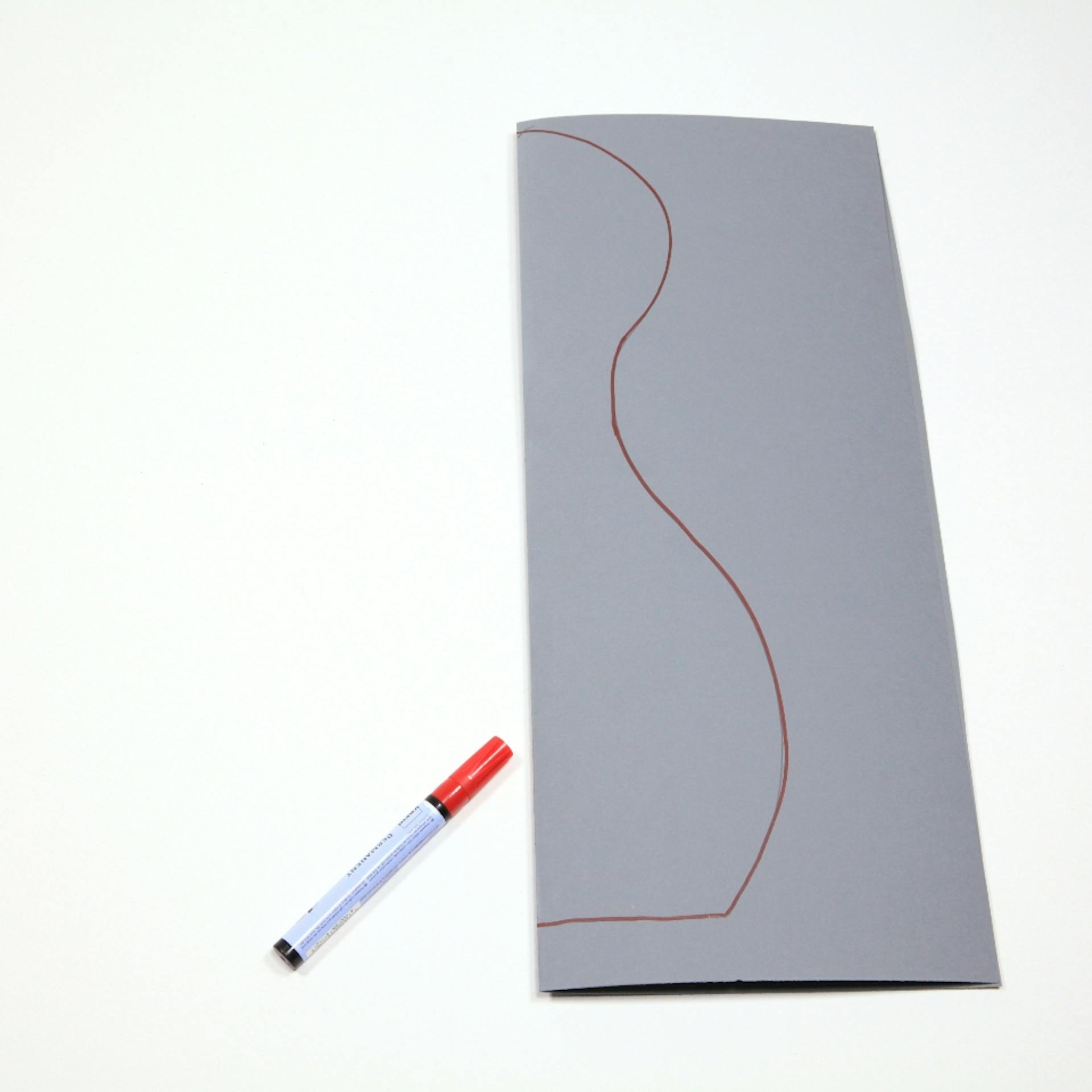 Graues, gefaltetes Stück Pappe mit Markierungen eines Kegels.