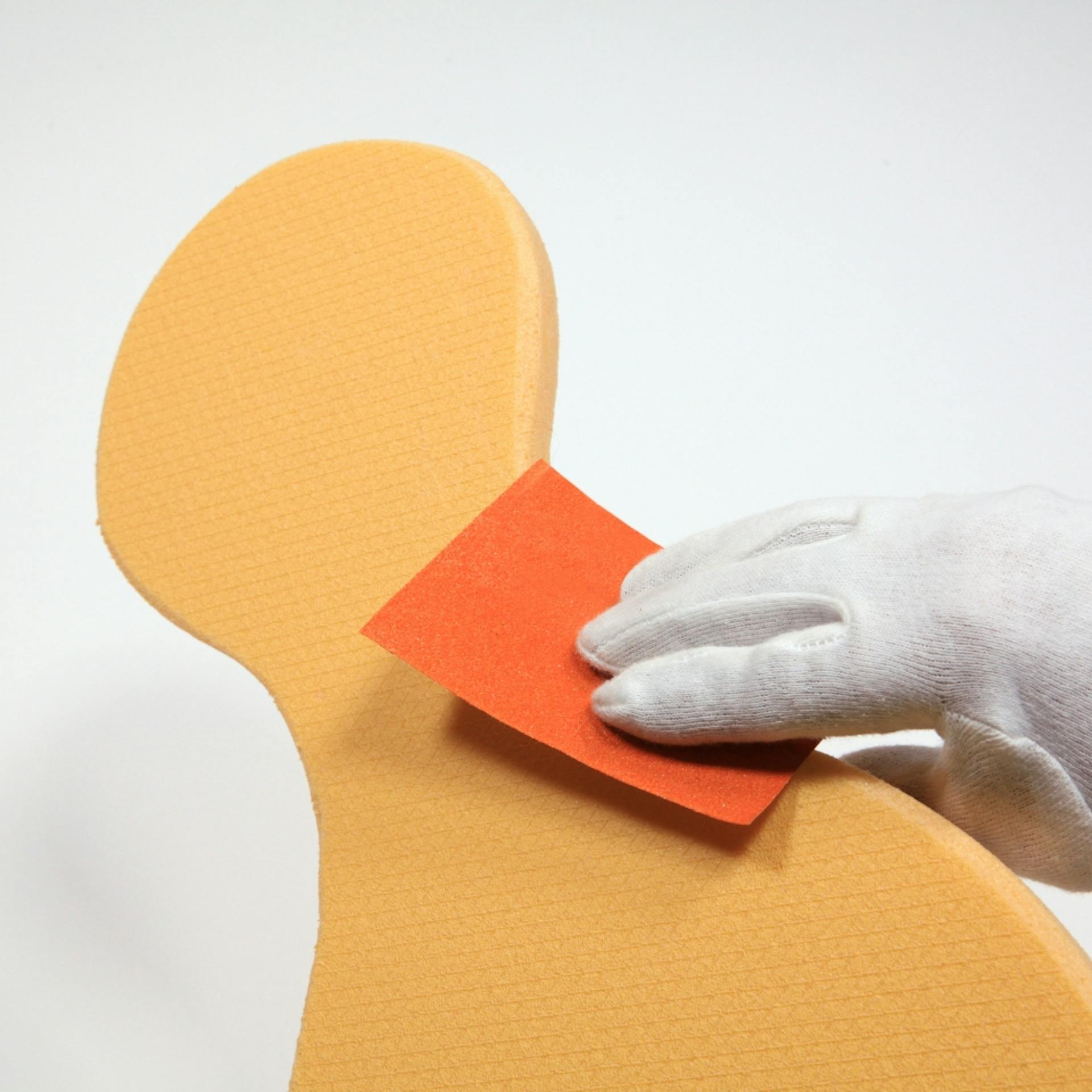 Jemand schleift eine Dämmplatte in Kegelform mithilfe von Schleifpapier.