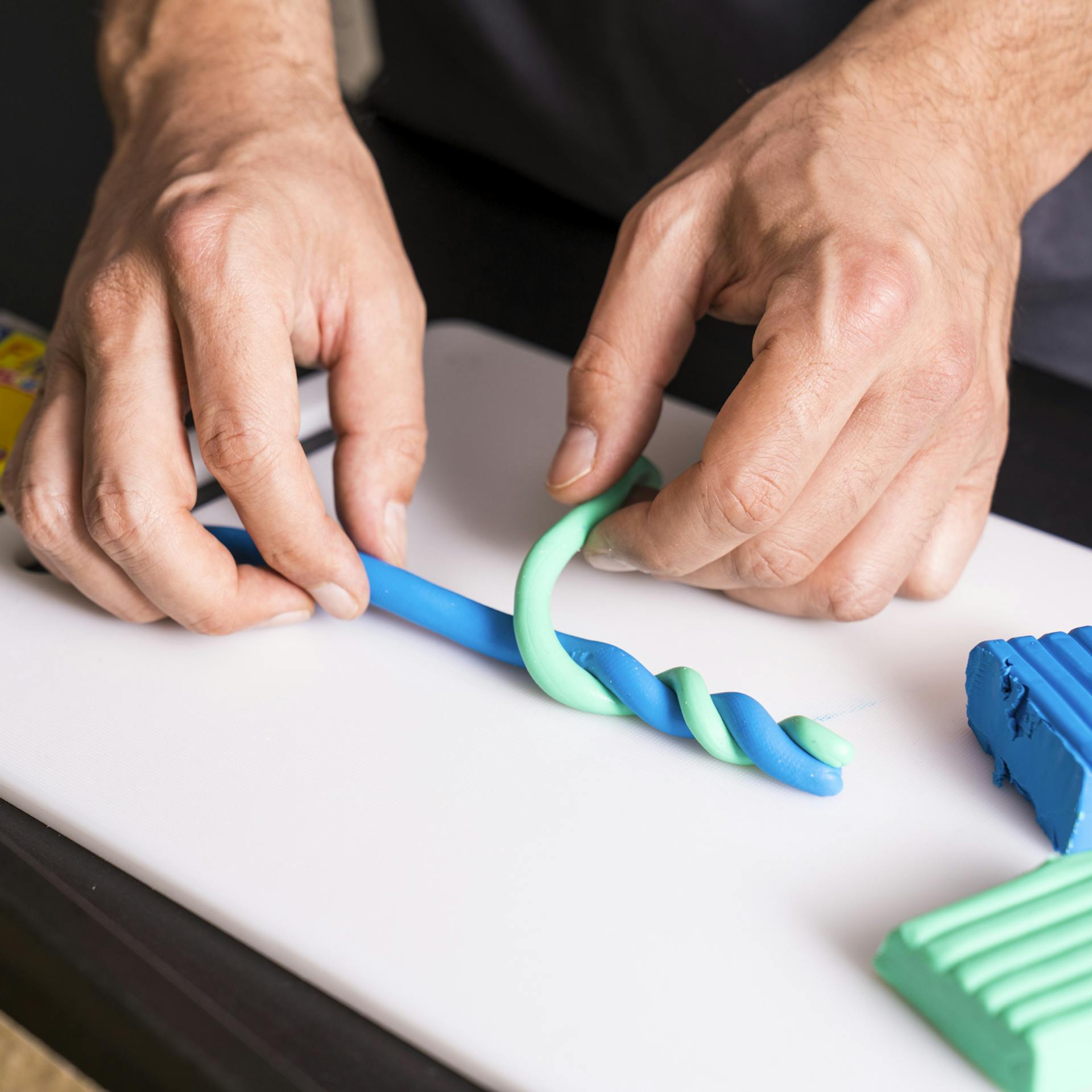 Zwei Farbstränge von Modelliermasse werden ineinander verschlungen