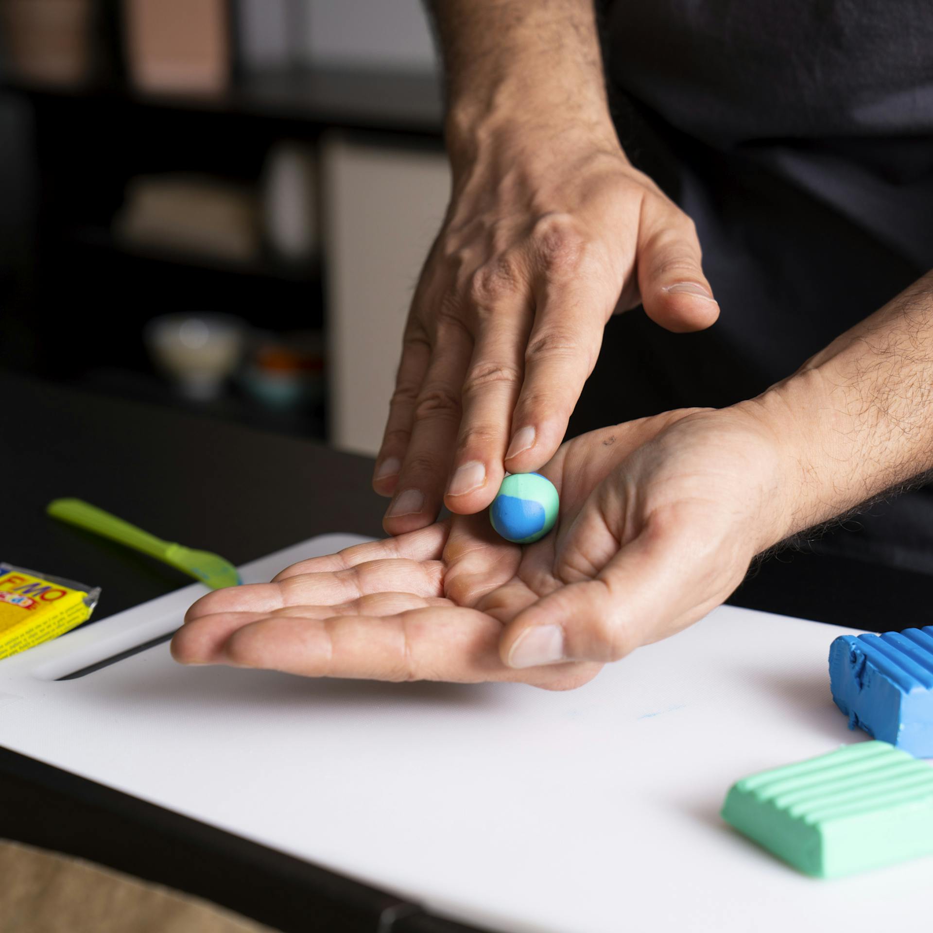 Hände formen Modelliermasse zu Murmel