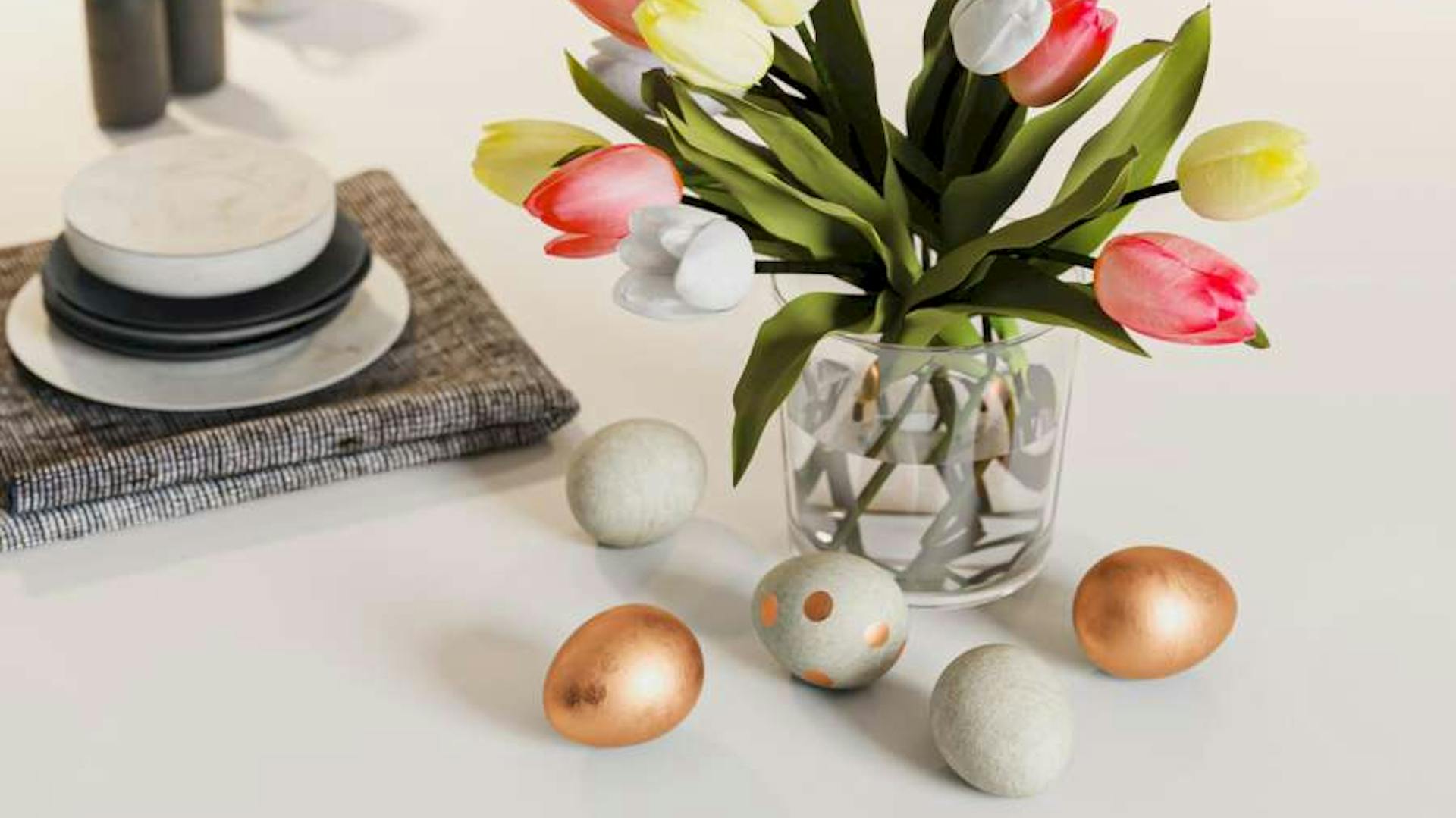 Runder Tisch mit Tulpen in Vase und selbst gebastelten Betoneiern auf dem Tisch.