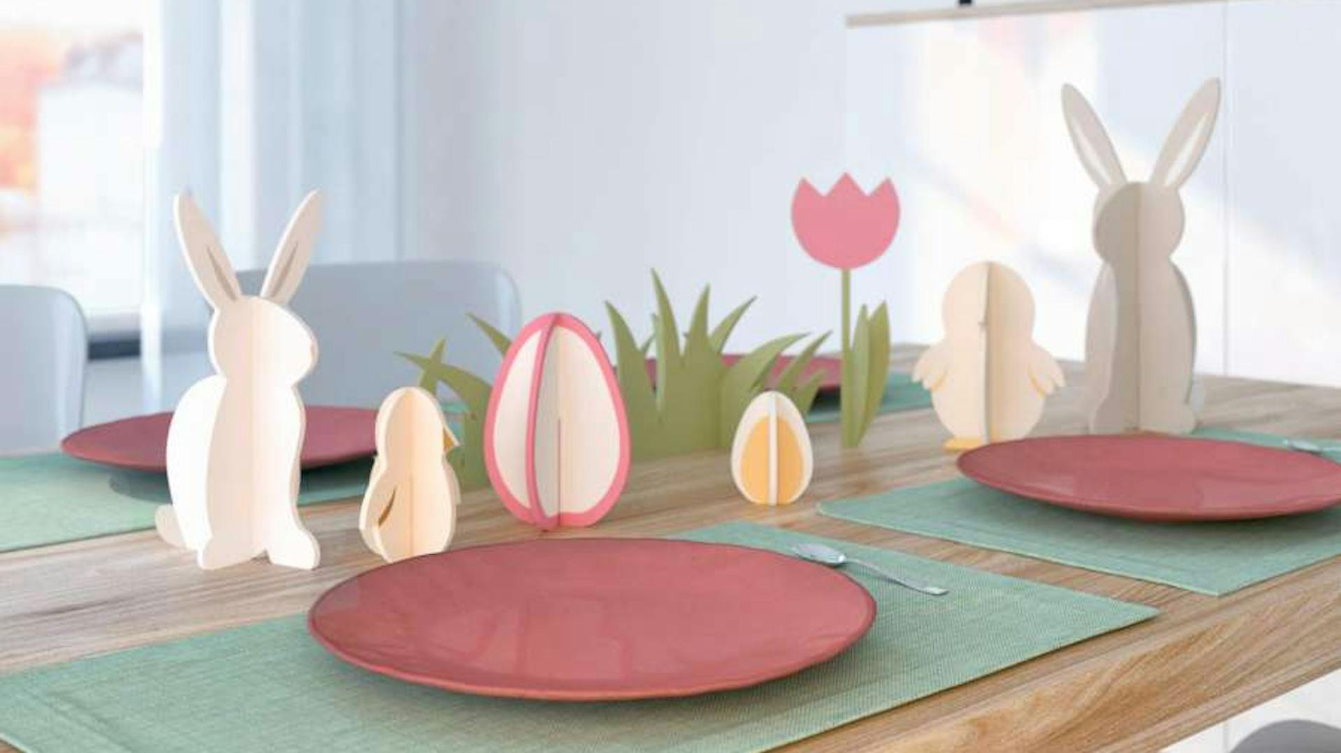 Gedeckter Tisch mit Untersetzern, Tellern und Osterdeko aus Holz in der Mitte.