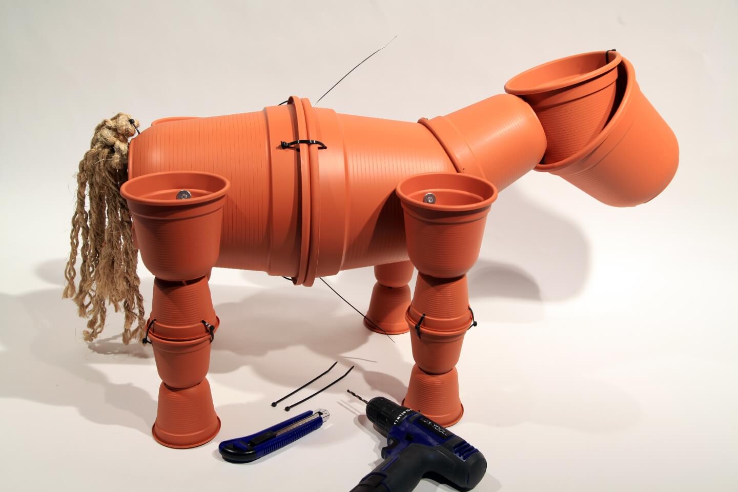 Cutter, Kabelbinder und Akkuschrauber neben Blumentopf-Pferd