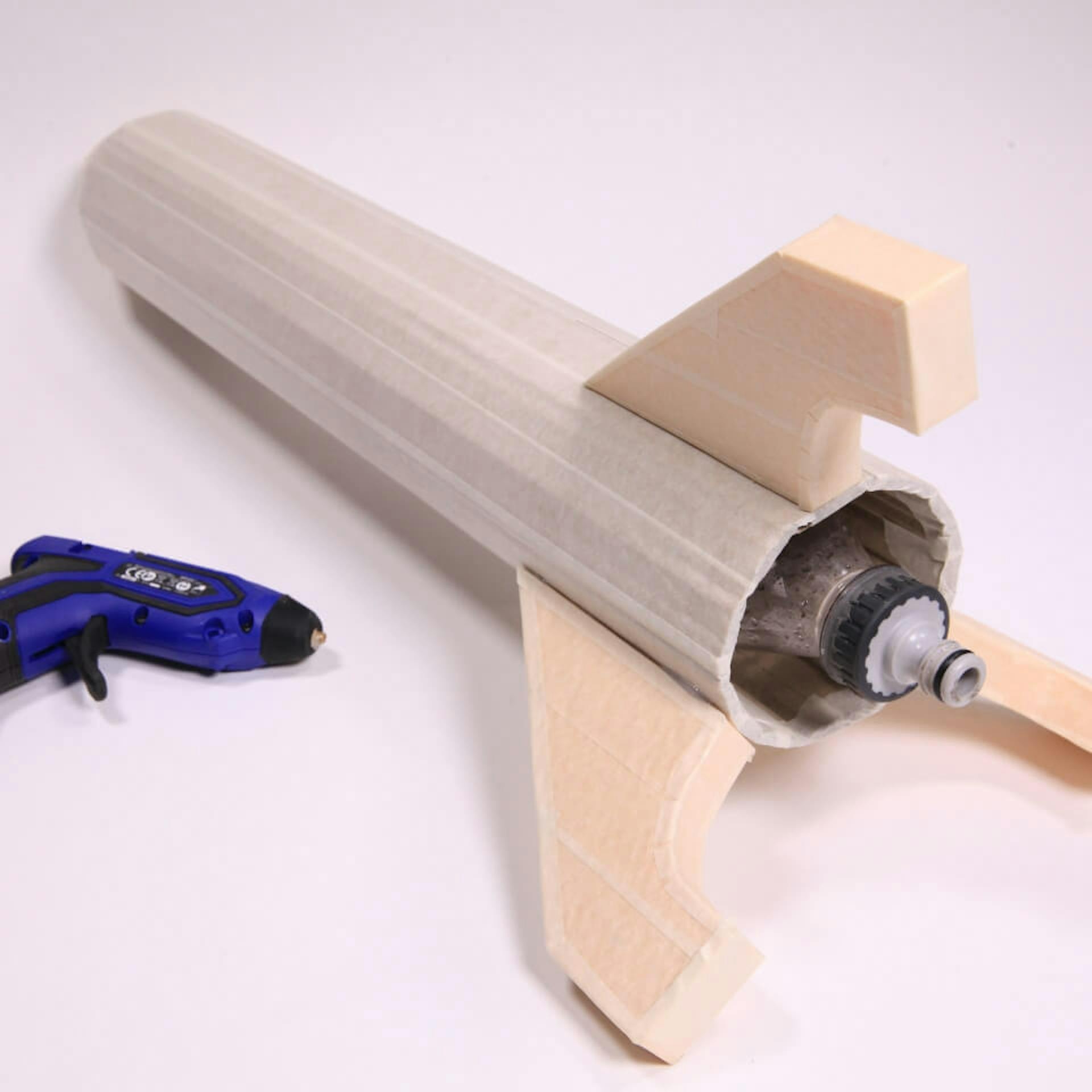 Drei Raketenflügel befestigt ans untere Ende des Raketenkörpers. Daneben liegt eine Heißklebepistole.