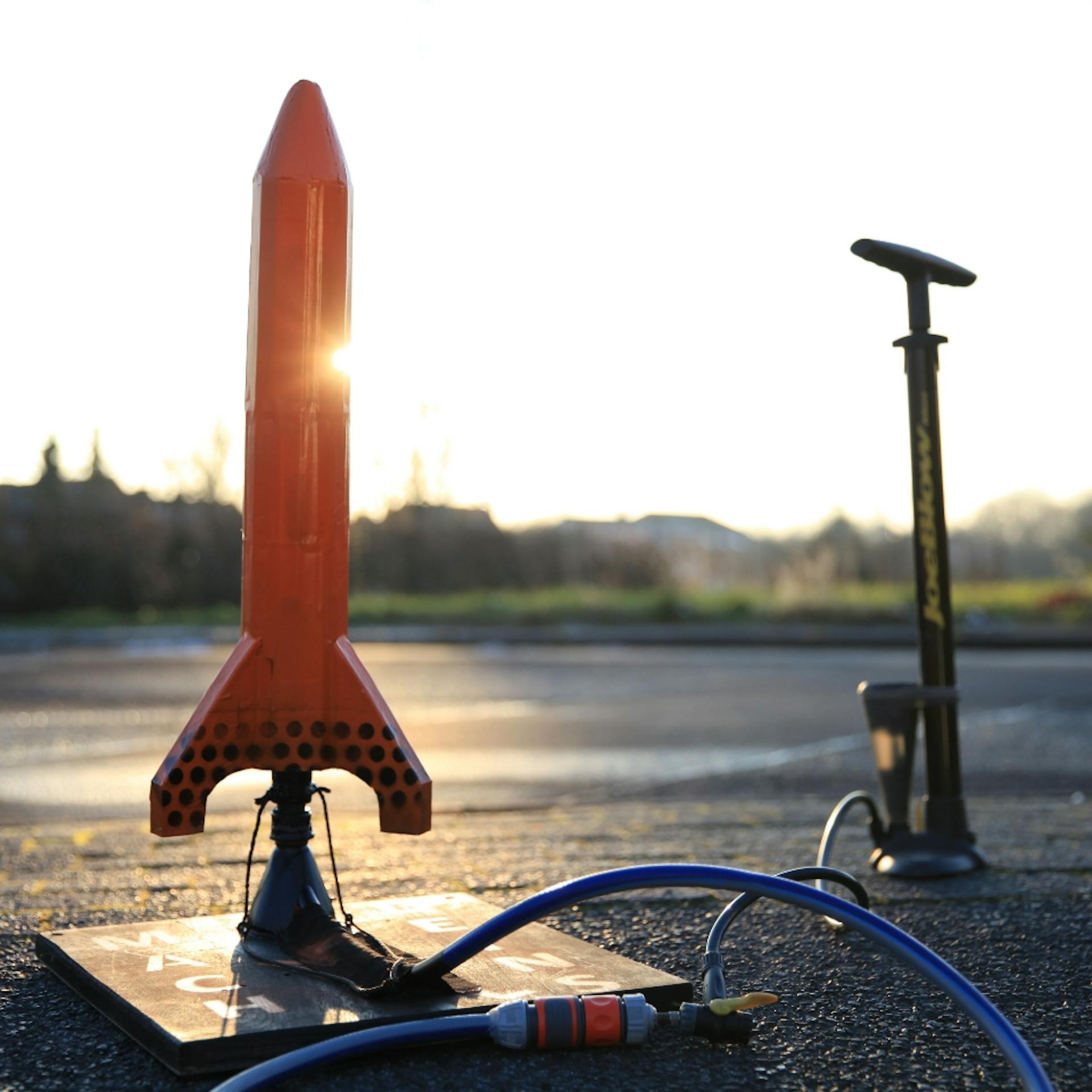 Fertig gebastelte Rakete steht auf dem Asphalt und ist mit einem Schlauch mit einer Luftpumpe verbunden.