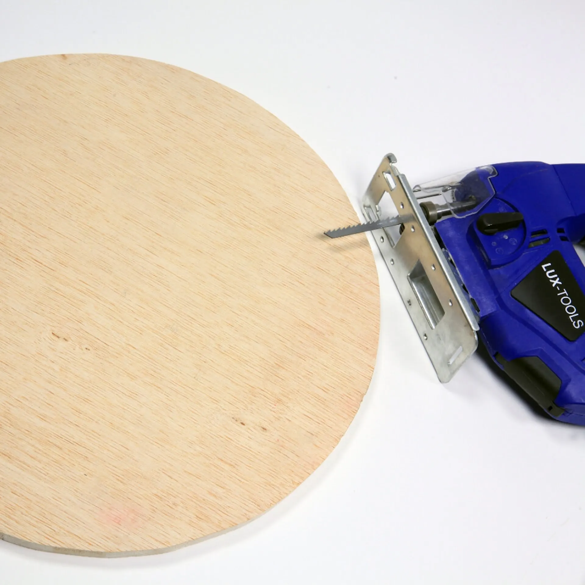 Stichsäge liegt neben runder Holzplatte.