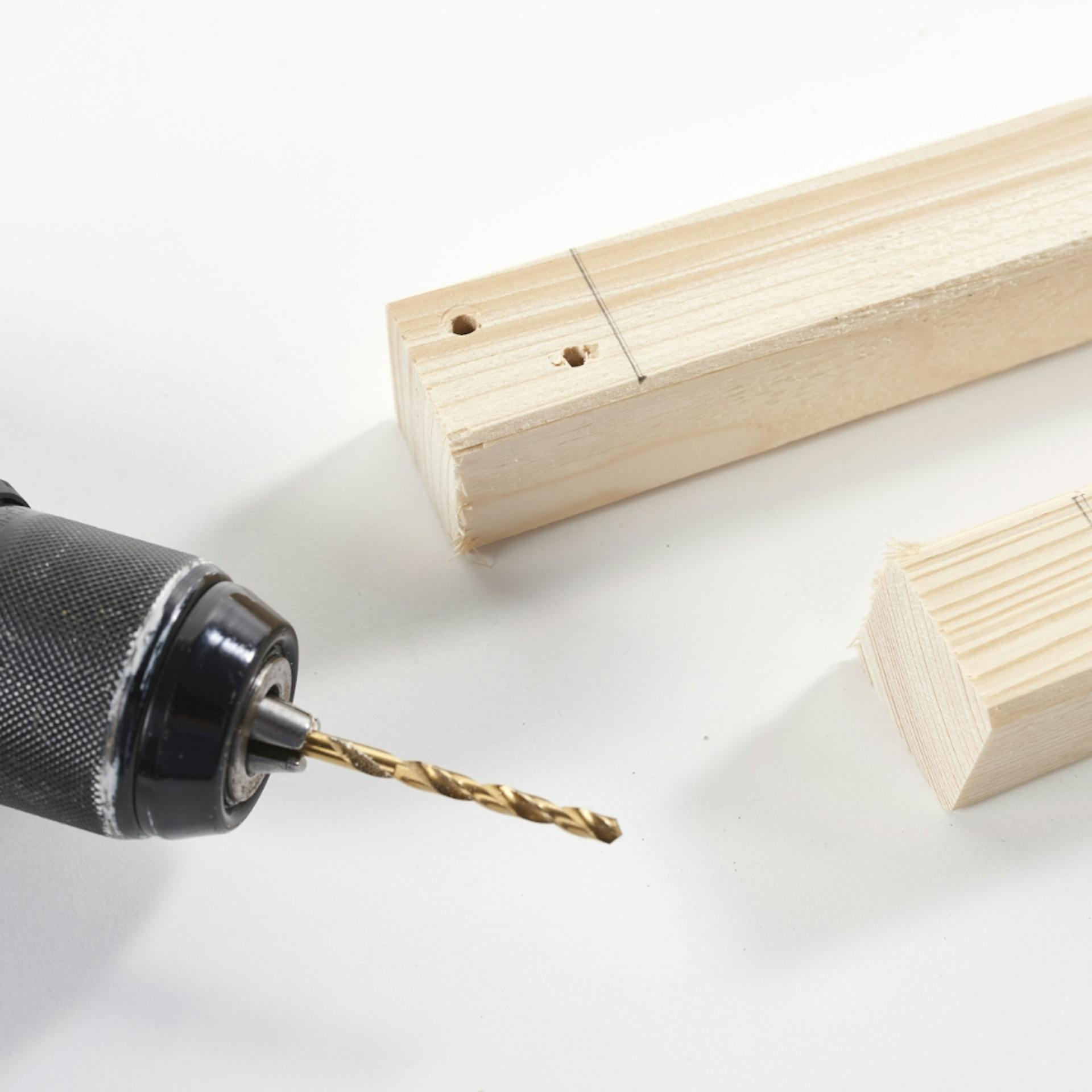 Kantholz mit zwei Löchern liegt neben Akkuschrauber