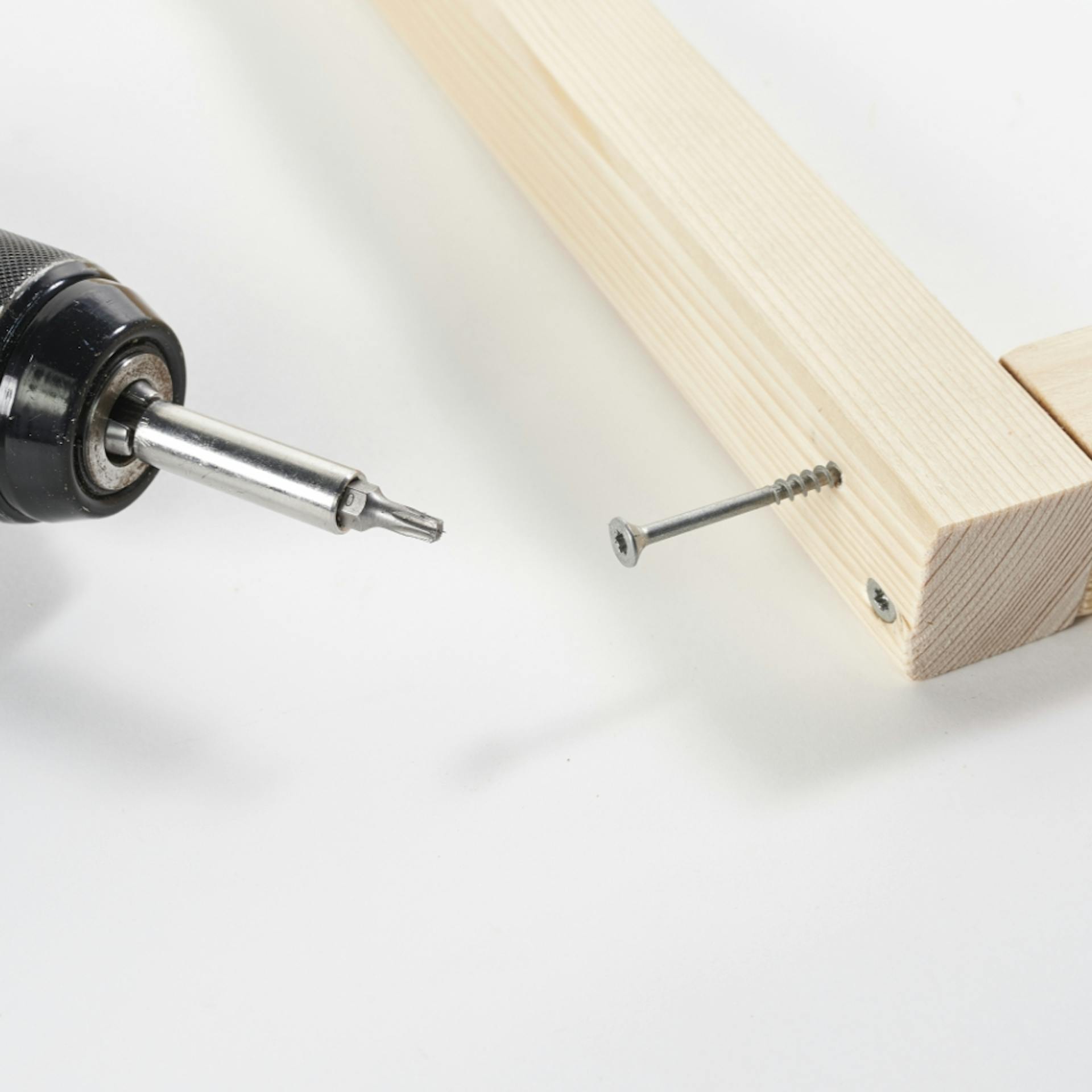 Schraube wird mit Akkuschrauber an Kantholz geschraubt