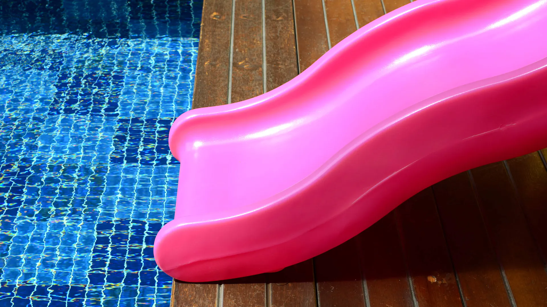 Piros műanyag csúszda a medence szélén.