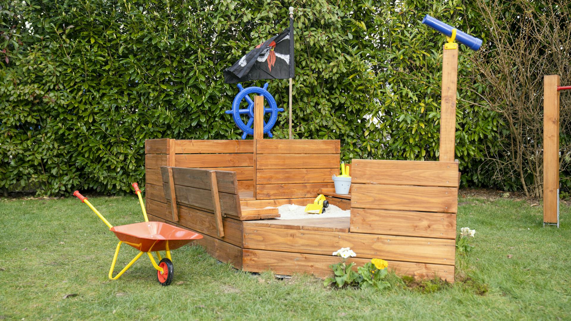 Drevené pieskovisko v tvare lode na lúke