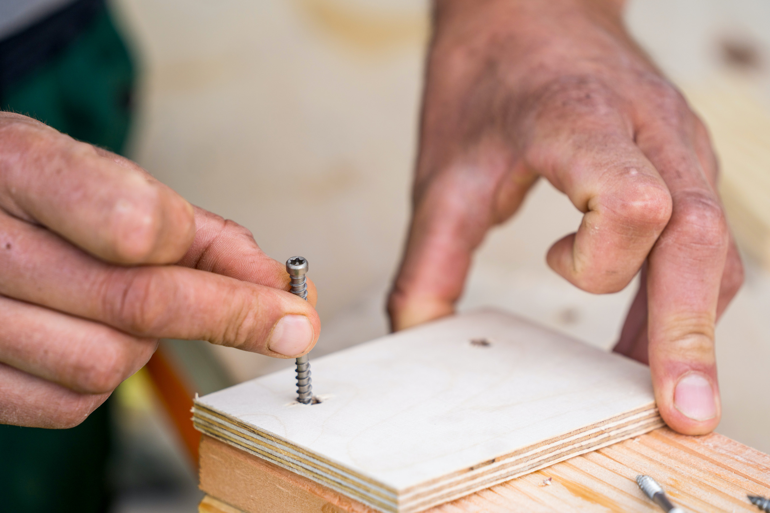 Una mano regge una vite nella dima di foratura