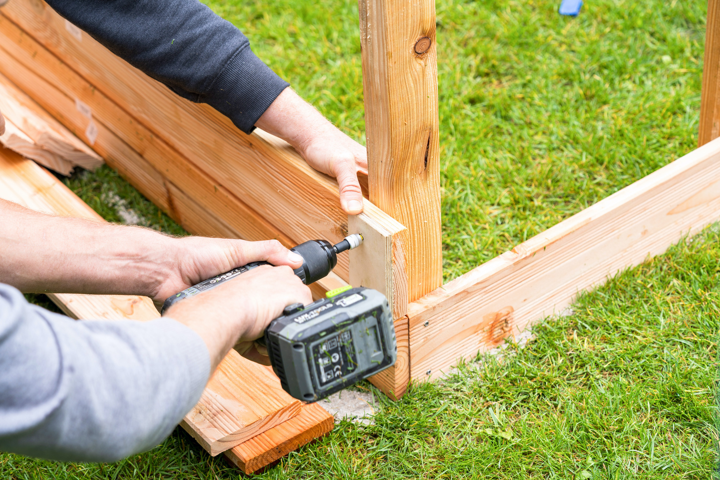 Mani avvitano assi di legno a una trave