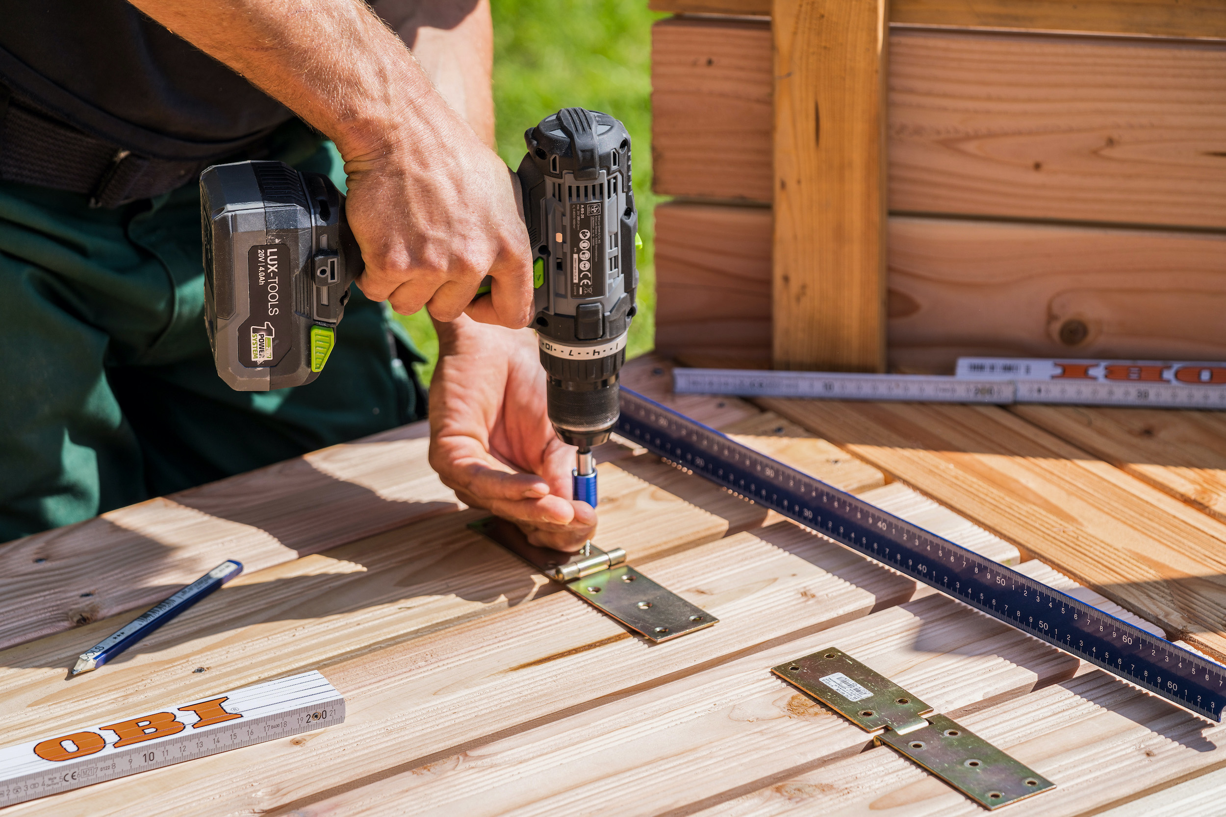 Mani avvitano delle cerniere su assi in legno