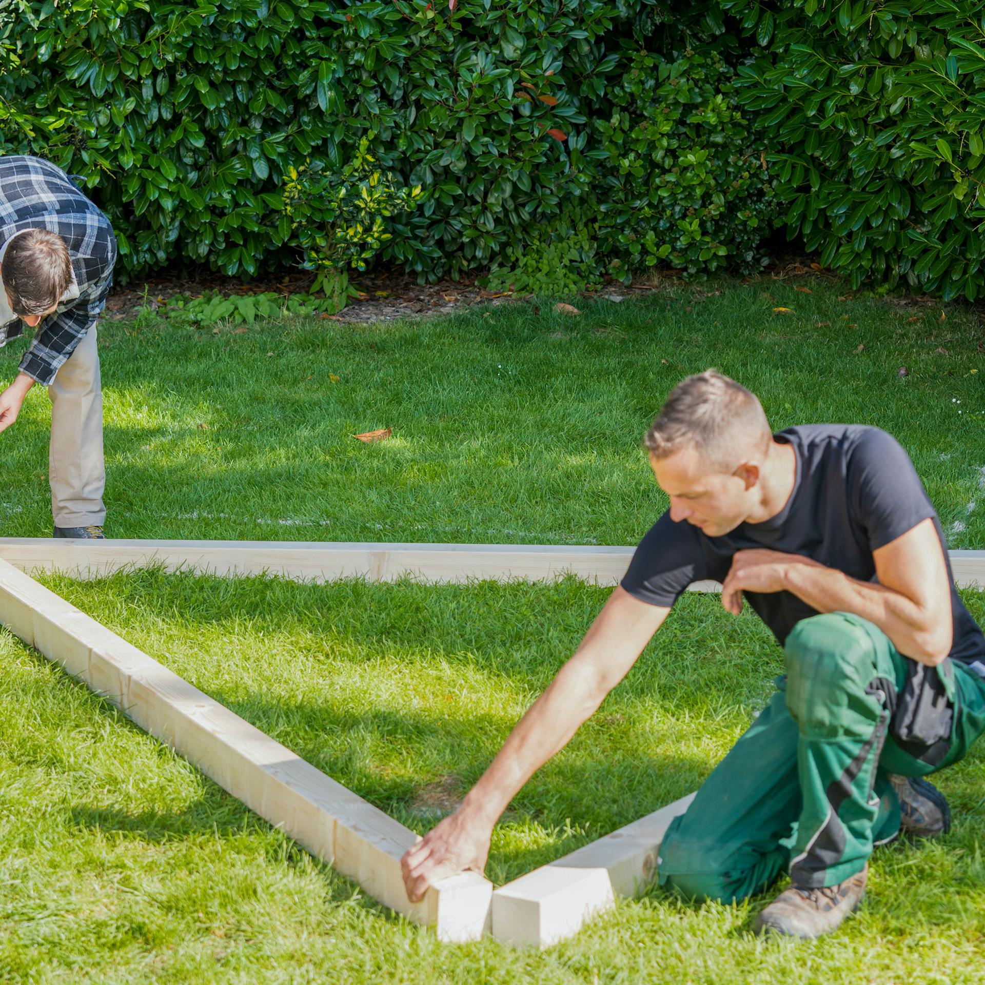 Férfiak fagerendákat helyeznek a gyepre
