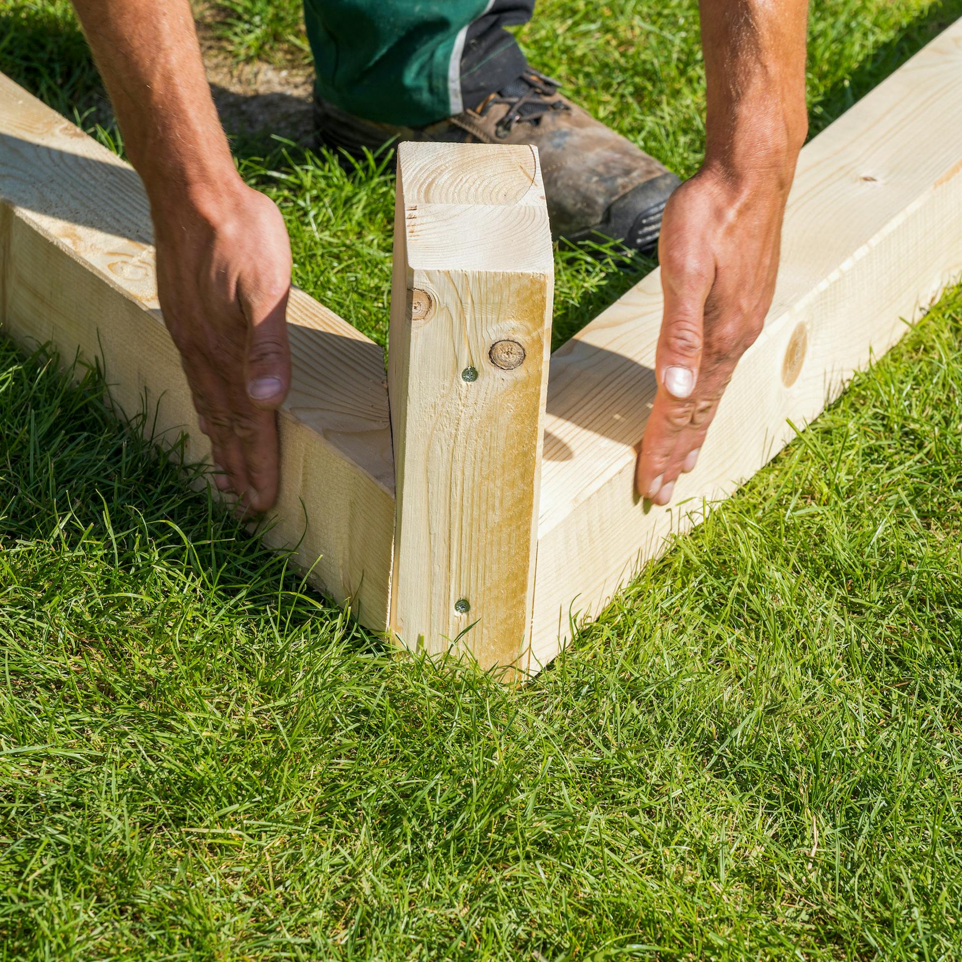 Kezek tartják a fagerendát a négyszögletes fához