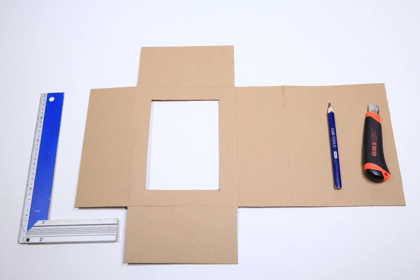 Vorlage für kleine Schießbude basteln neben Cutter, Bleistift und Winkel auf Tisch.
