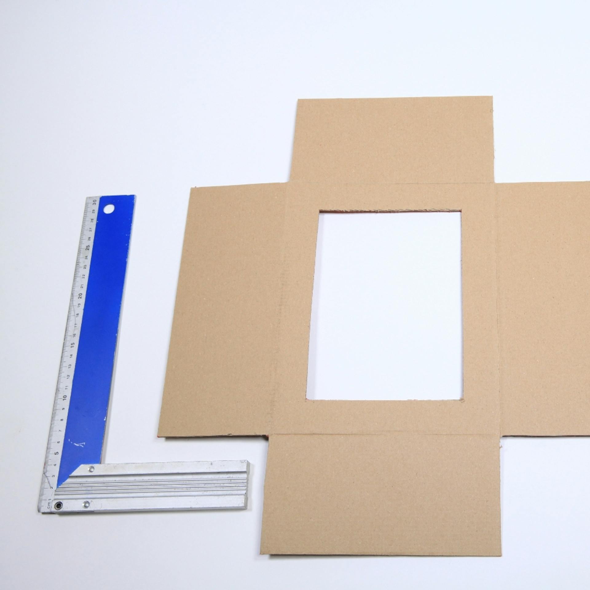 Vorlage für kleine Schießbude basteln neben Cutter, Bleistift und Winkel auf Tisch.