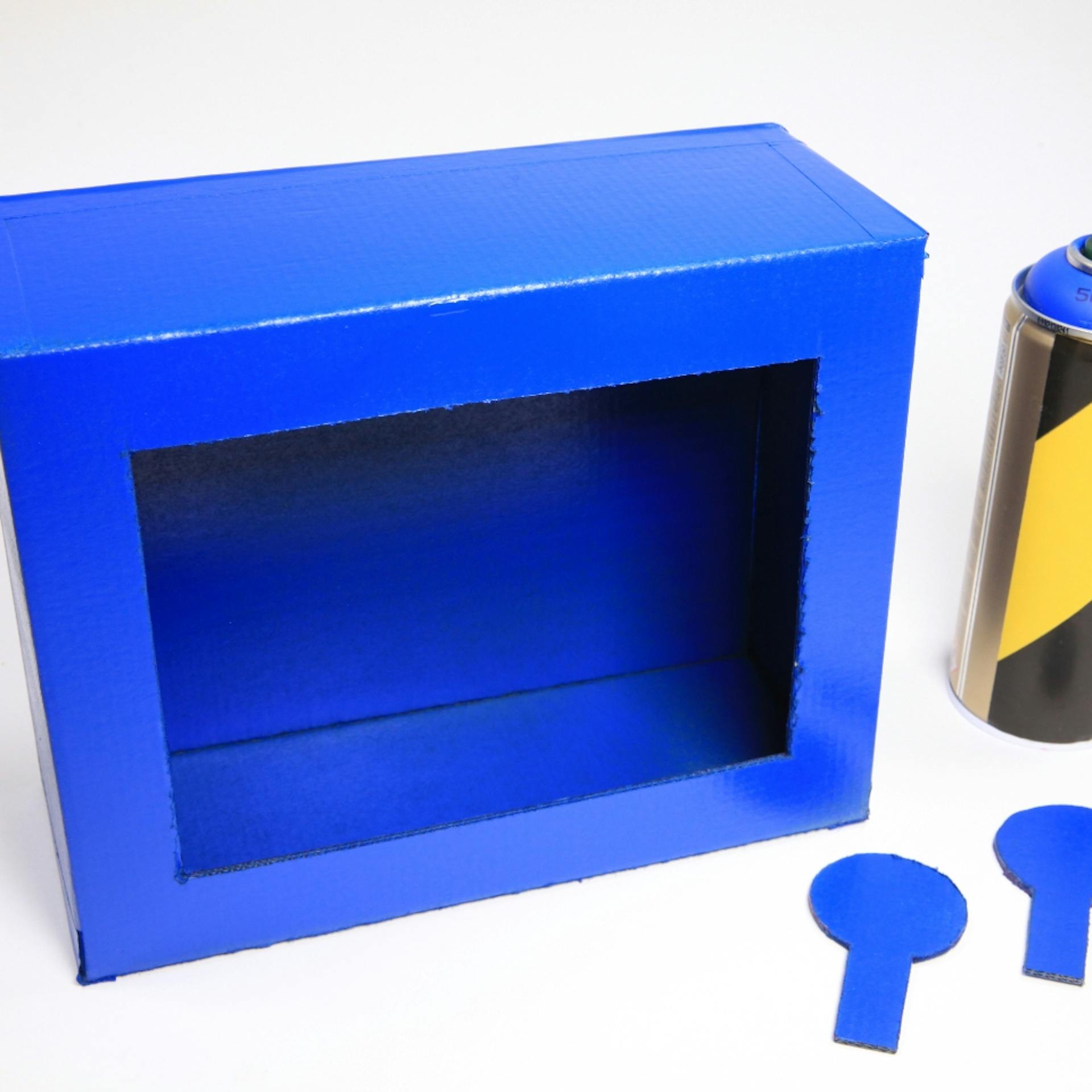 Schuhschachtel blau besprüht steht neben Sprühdose