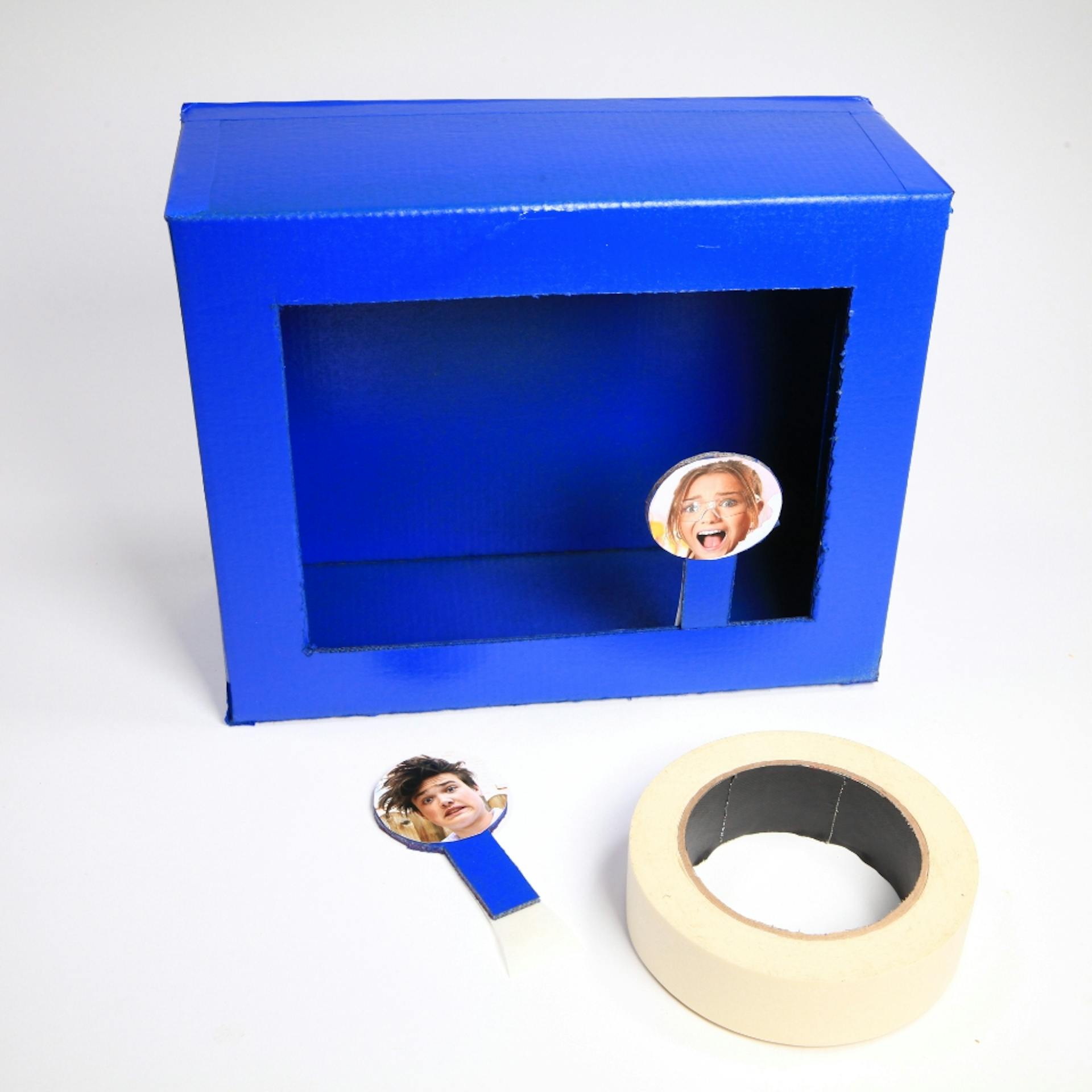 Blauer Schuhkarton mit Ziel als Schießbude neben Klebeband-Rolle