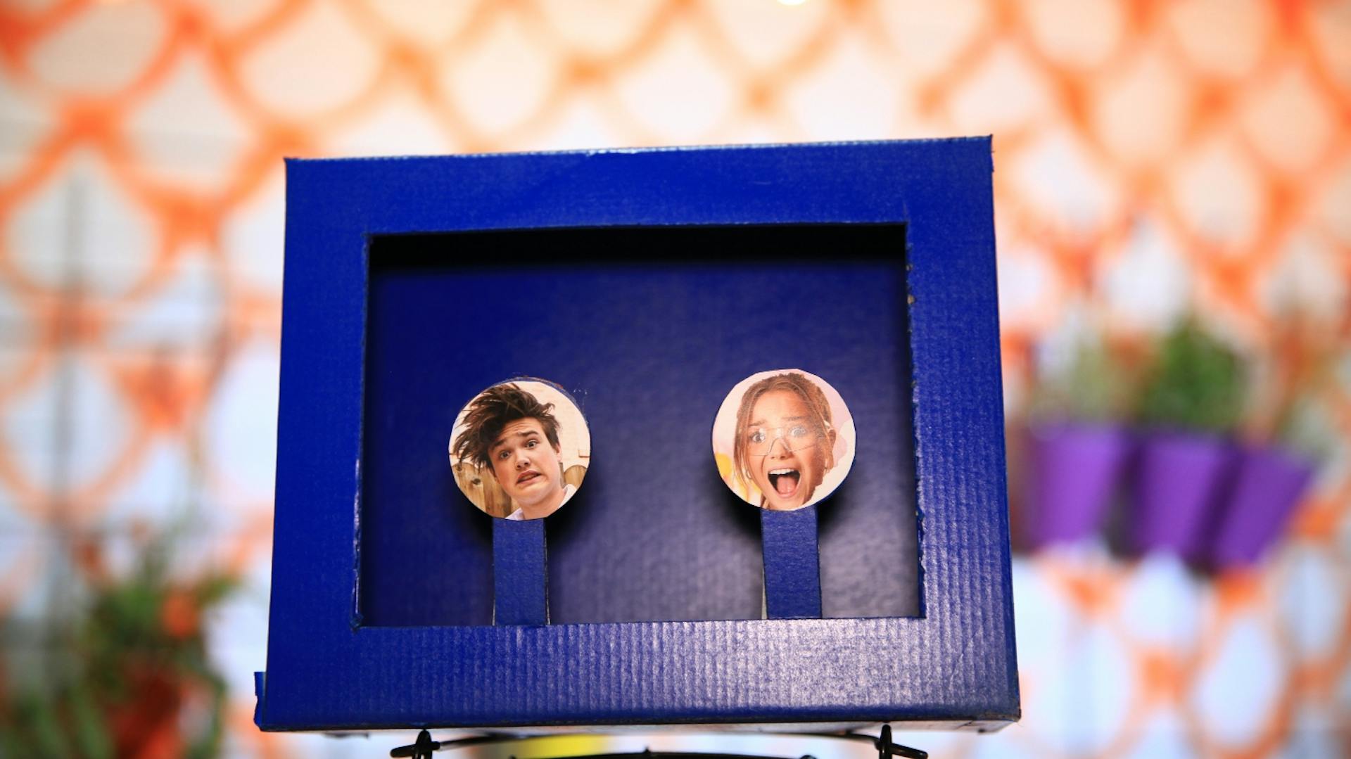 Selbstgebaute Schießbude aus Schuhkarton blau bemalt mit zwei Gesichtern als Ziel