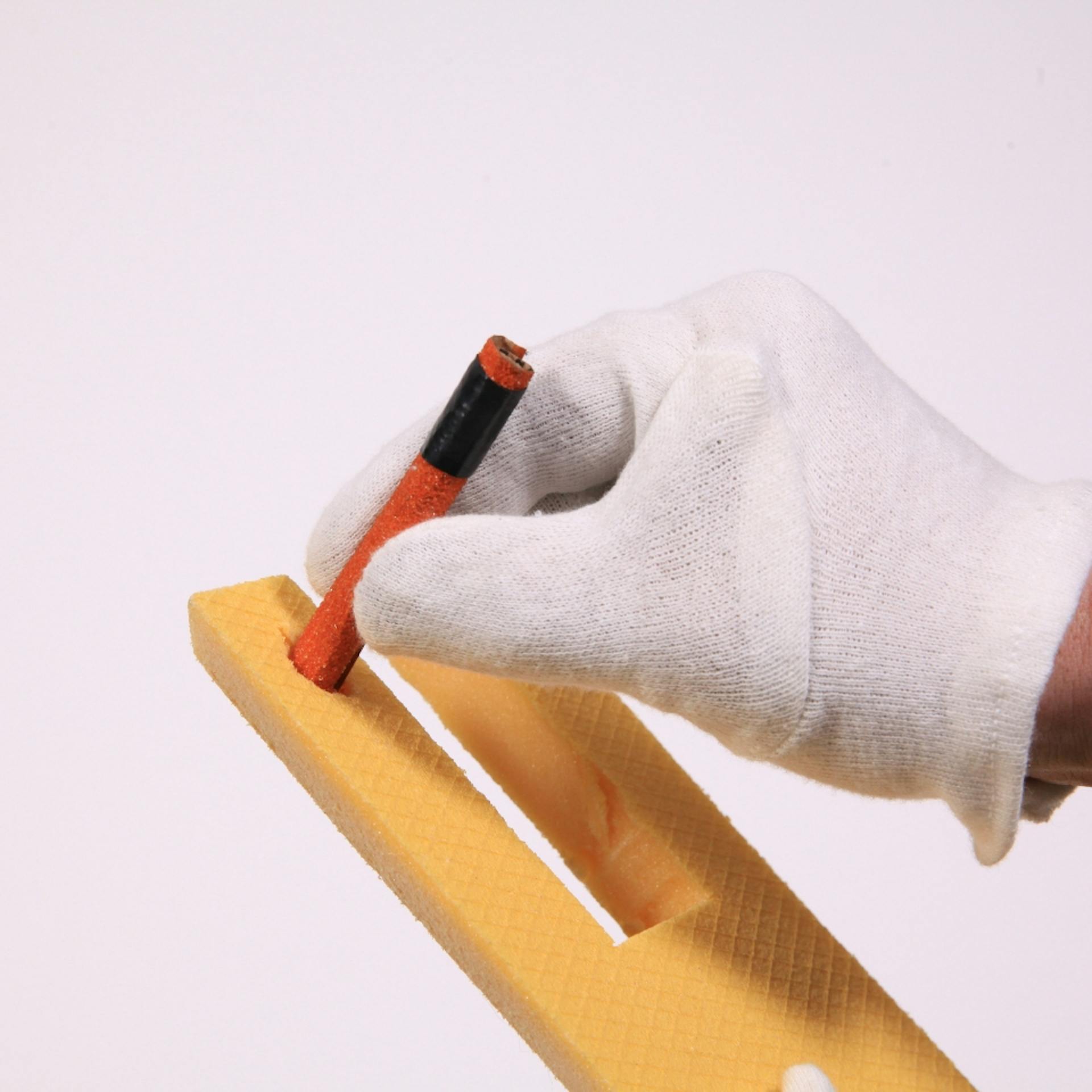 Person bohrt ein Stück Schleifpapier durch Dämmplatte