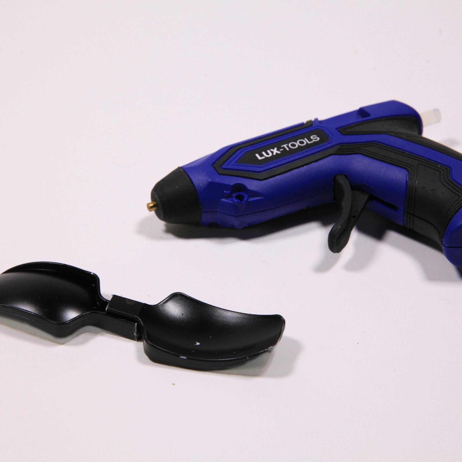 Heißklebepistole liegt neben zwei Löffeln aus Plastik