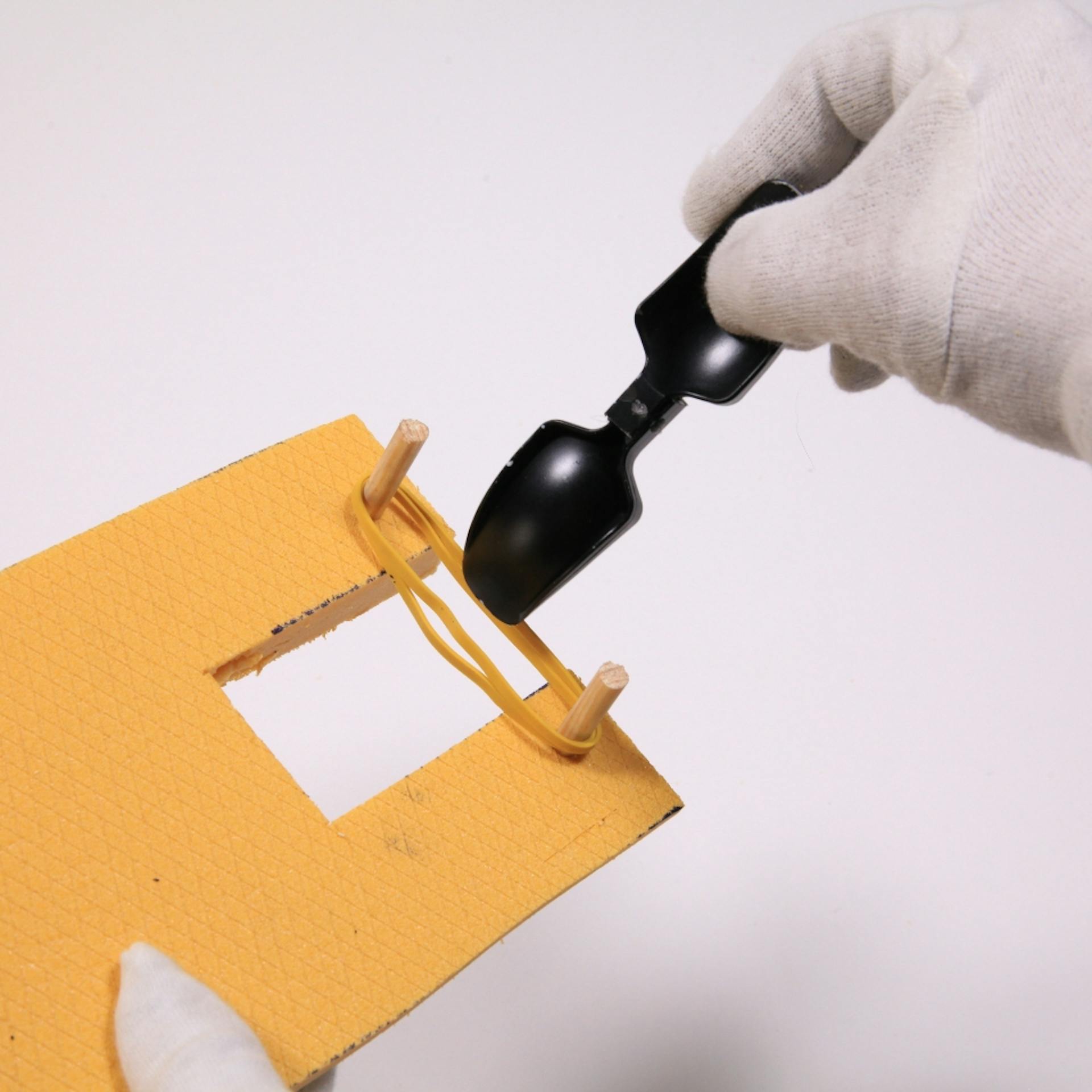 Plastiklöffel wird an Gummiband befestigt