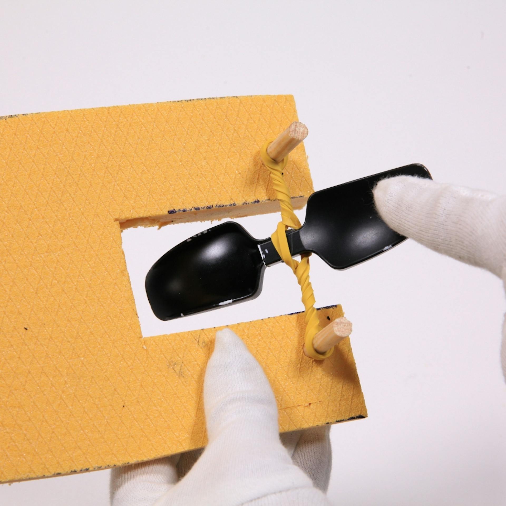 Plastiklöffel wird mit Gummiband strammgezogen