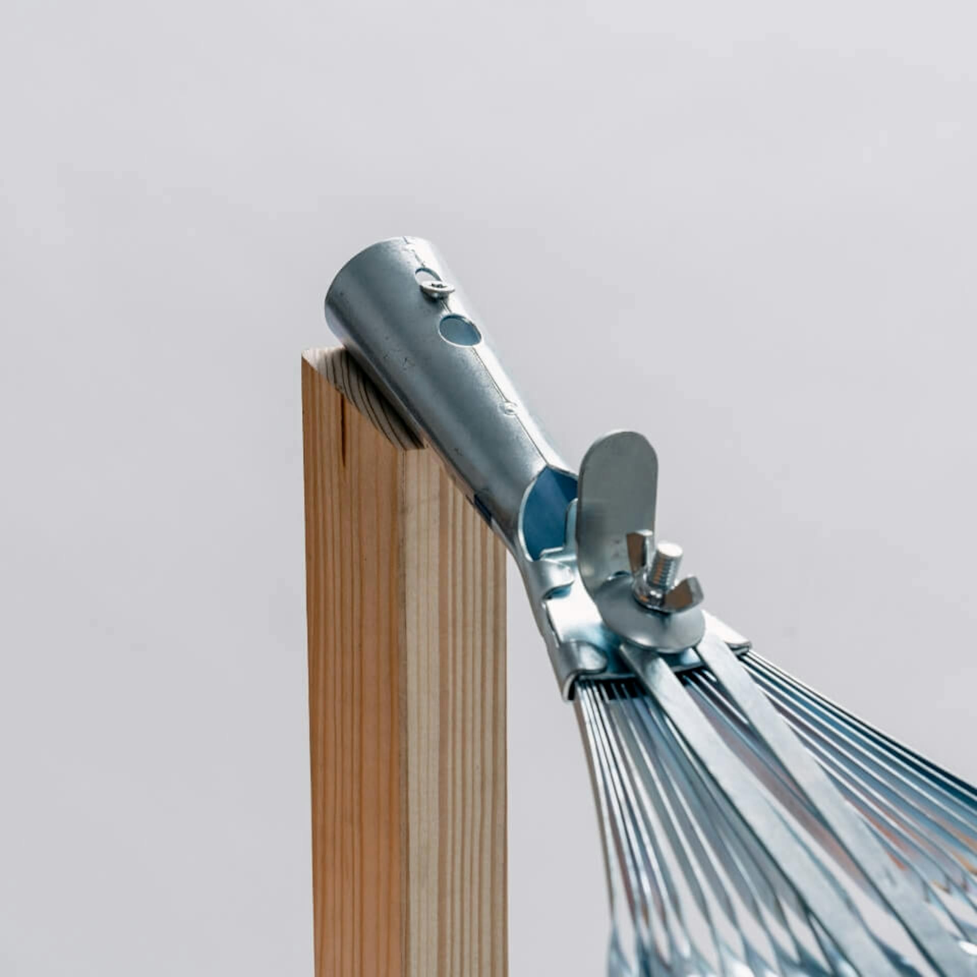 Es ist ein Holzstab zu sehen, an welchem ein Rechen befestigt ist.