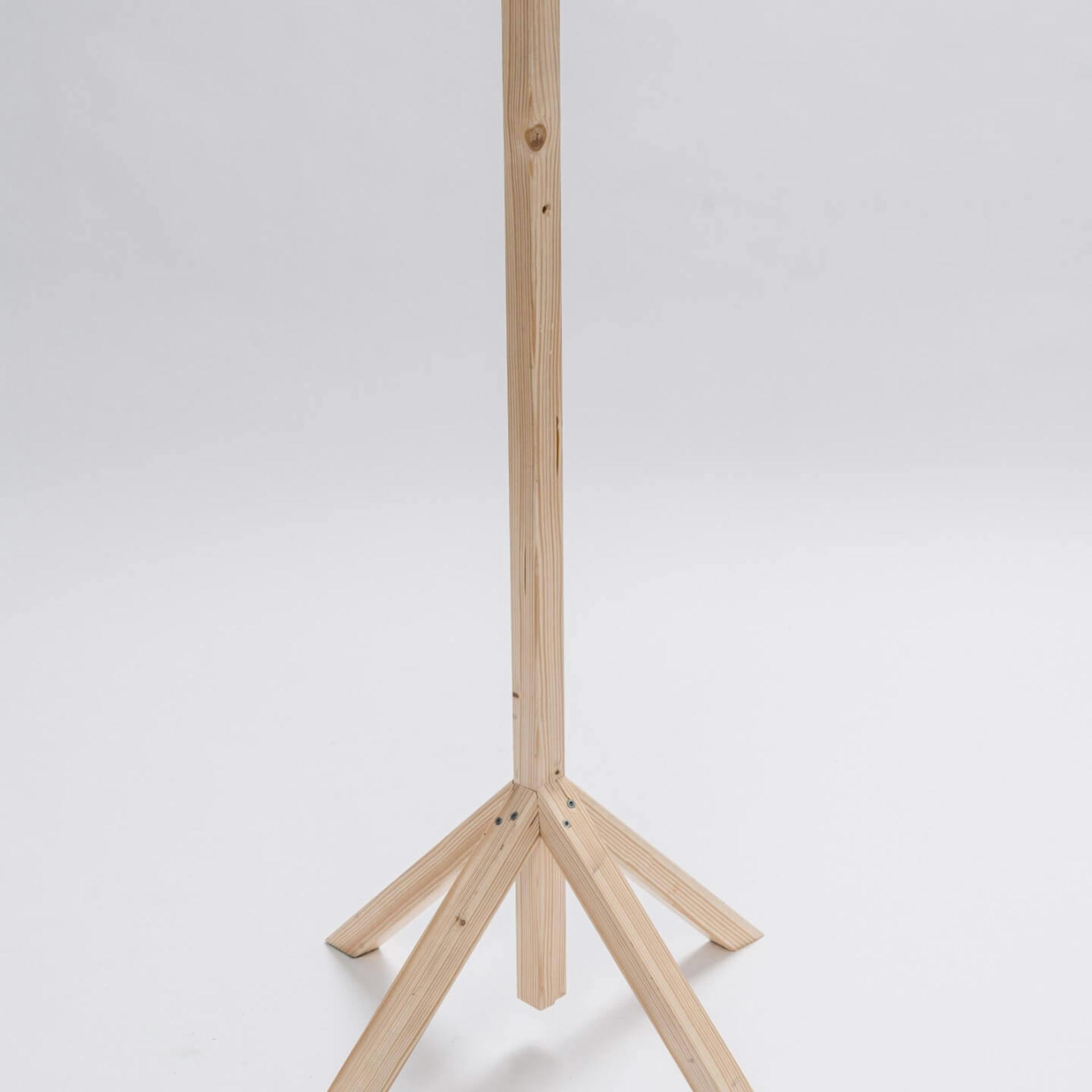 Vor hellem Hintergrund steht ein Ständer aus Holz mit vier Holzfüßen.