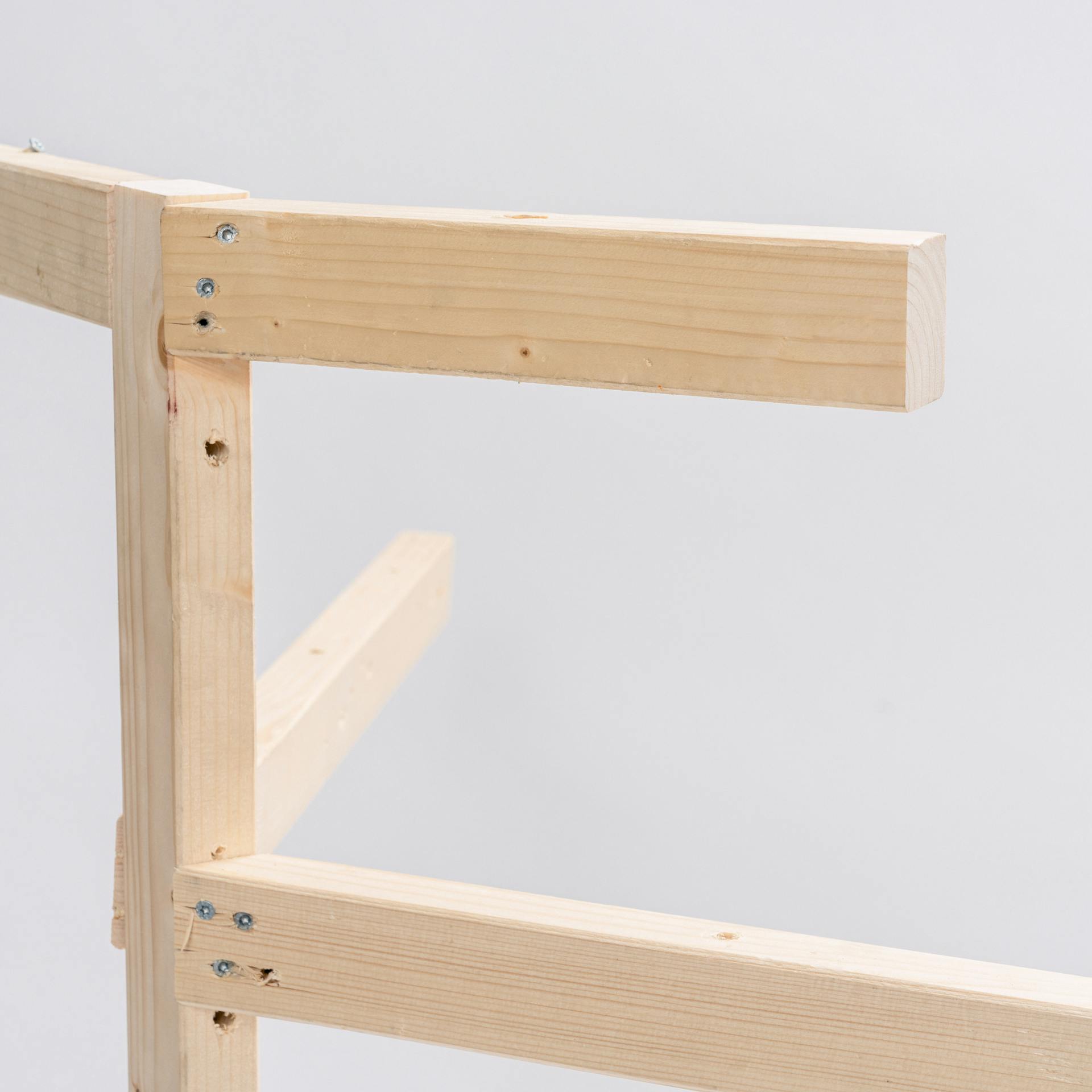 Es ist ein Kantholz zu sehen. Mittig sowie am oberen Ende des Kantholzes sind jeweils zwei weitere Kanthölzer mit Schrauben befestigt.